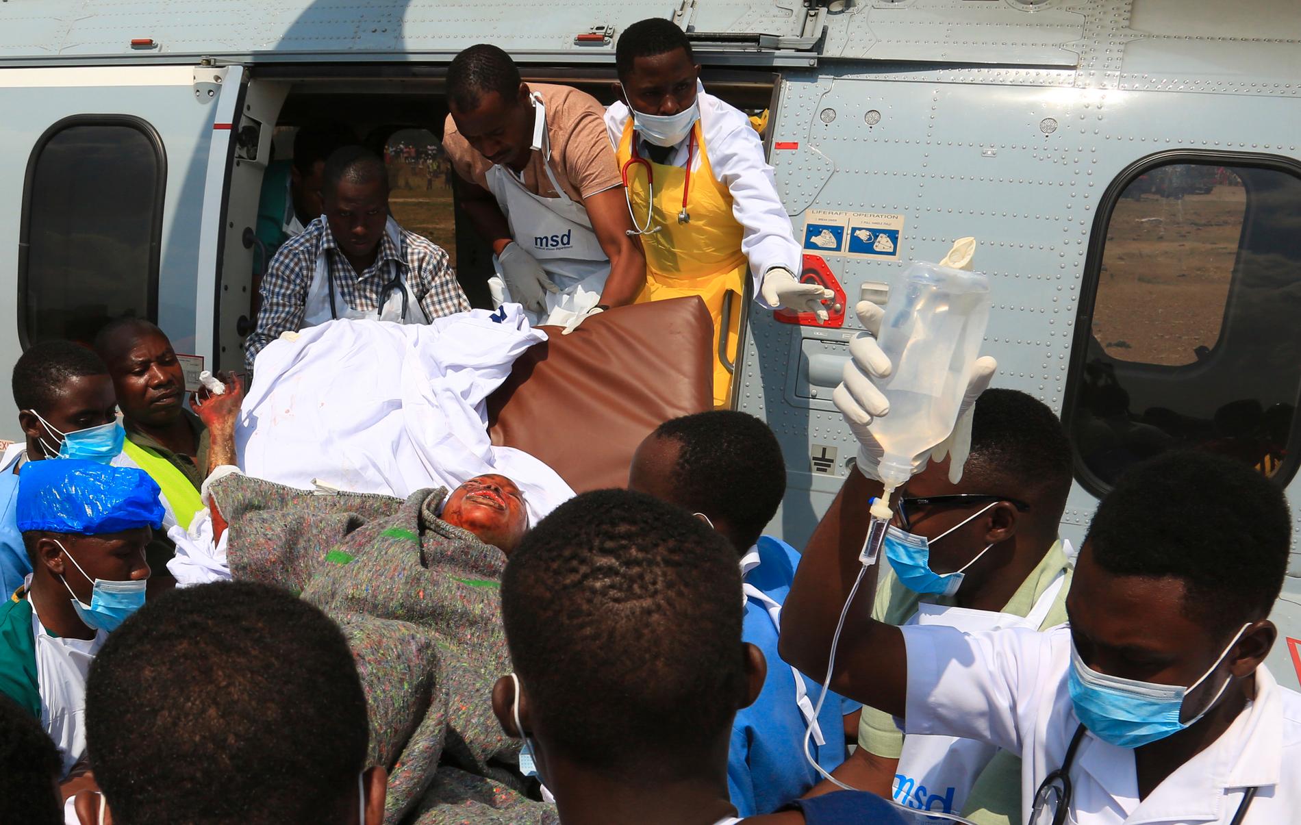 Vårdarbetare bär en skadad man som fraktats med militärhelikopter till Dar es-Salaam.