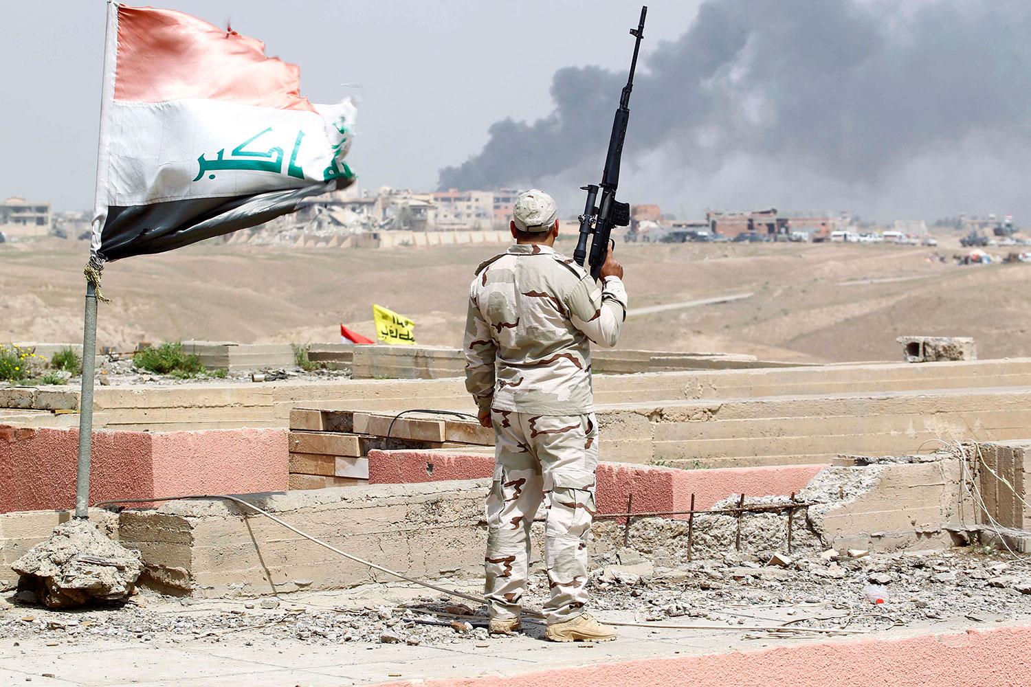 En milisman ser rök stiga från Tikrit.