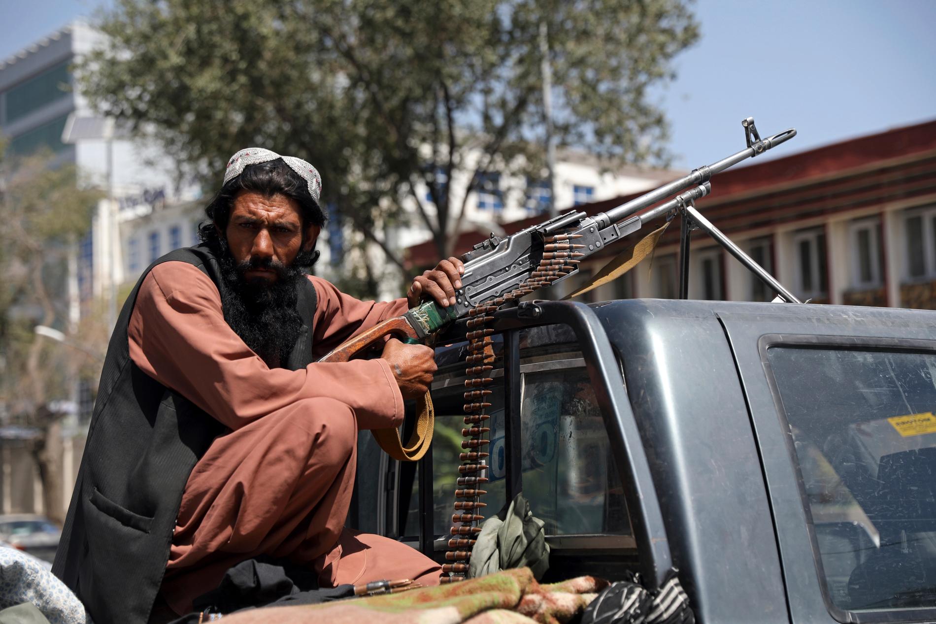 En taliban står med med vapen utanför  presidentpalatsets huvudgrind för att se till att ingen kommer in.