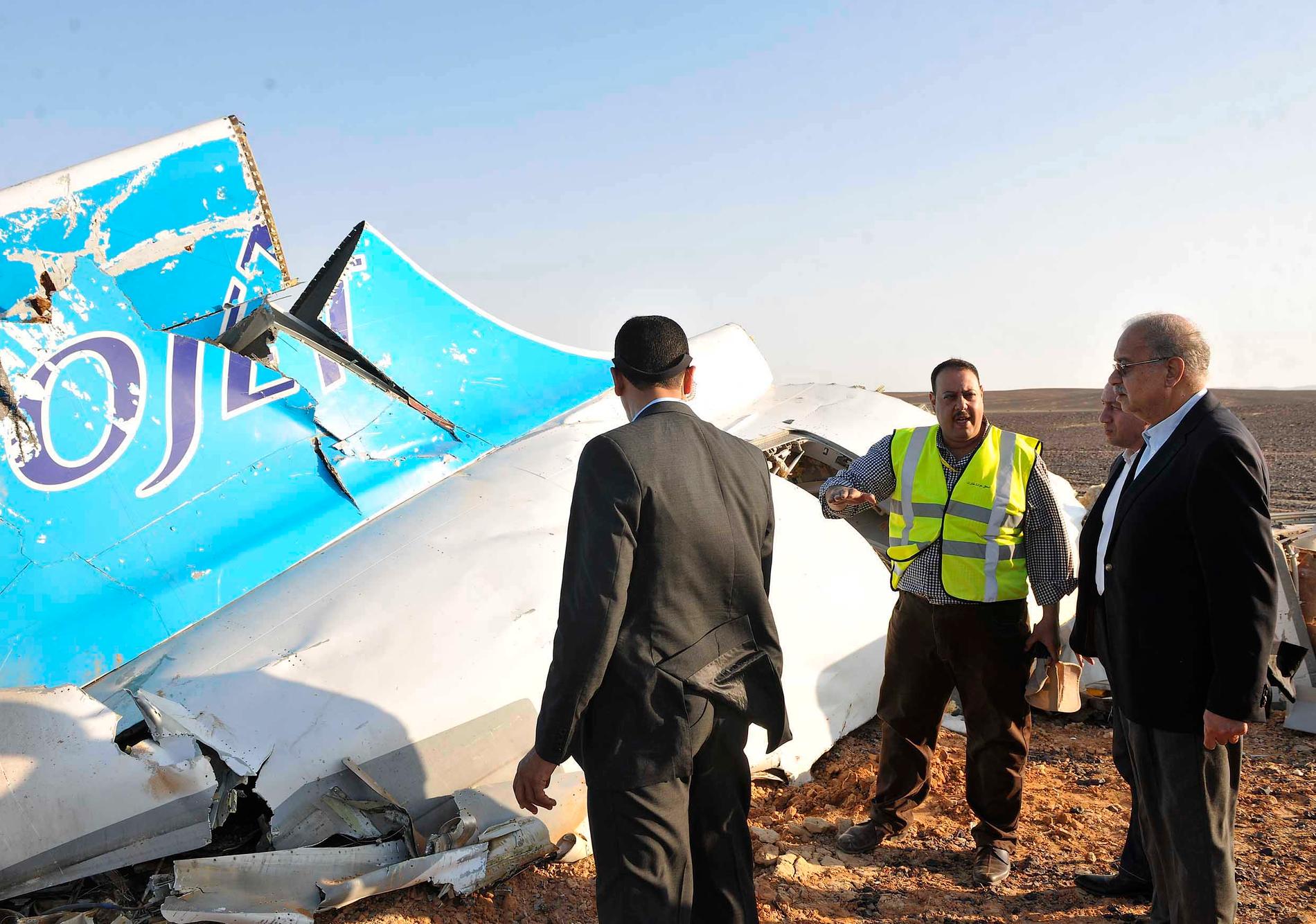 Egyptiska politiker och tjänstemän inspekterar vrakdelarna av det ryska passagerarflygplan som sköts ned över Sinaihalvön, i oktober 2015. Fler än 200 människor dödades när en sprängladdning ombord tros ha detonerat under resan. Arkivbild.