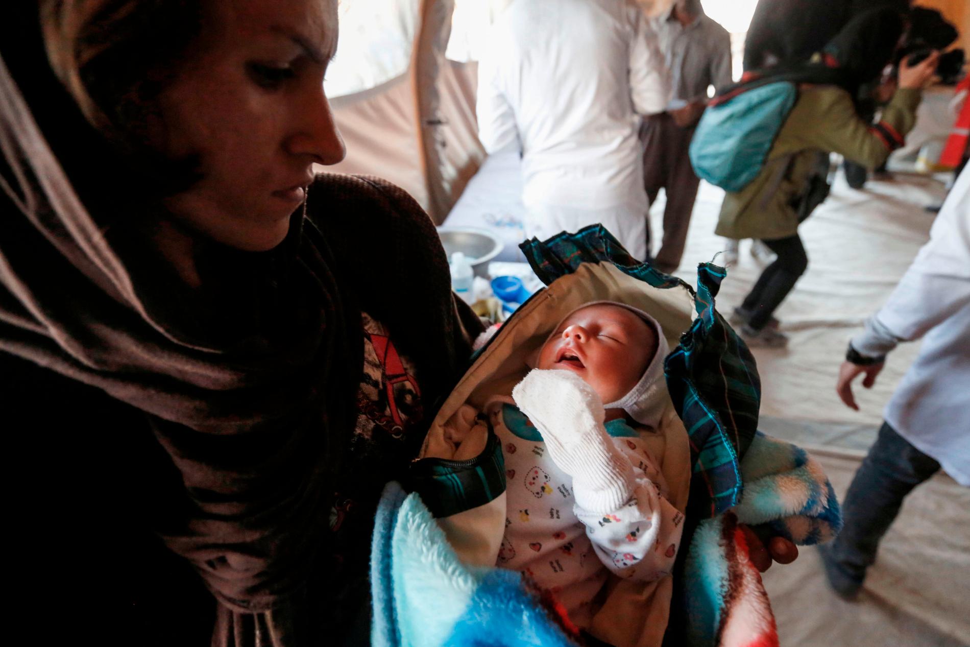 En kvinna håller ett nyfött barn på ett sjukhus i staden Sarpol-e Zahab.