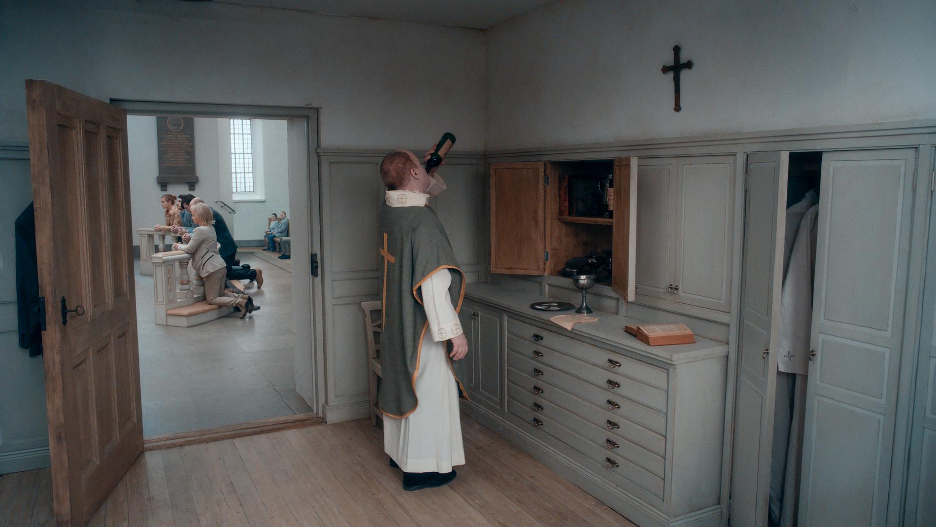 En präst, som häller i sig nattvardsvinet för att dränka ångesten efter att ha förlorat sin tro, avbildas på en av Anderssons bilder. Pressbild.