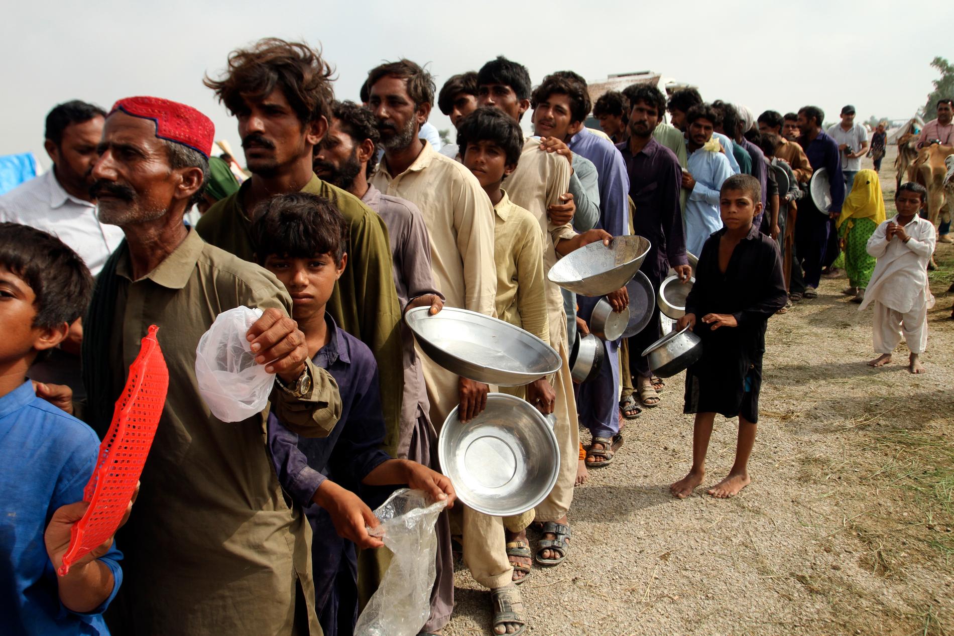 Människor som tvingats lämna sina hem köar för mat i Rajanpur i Punjab.