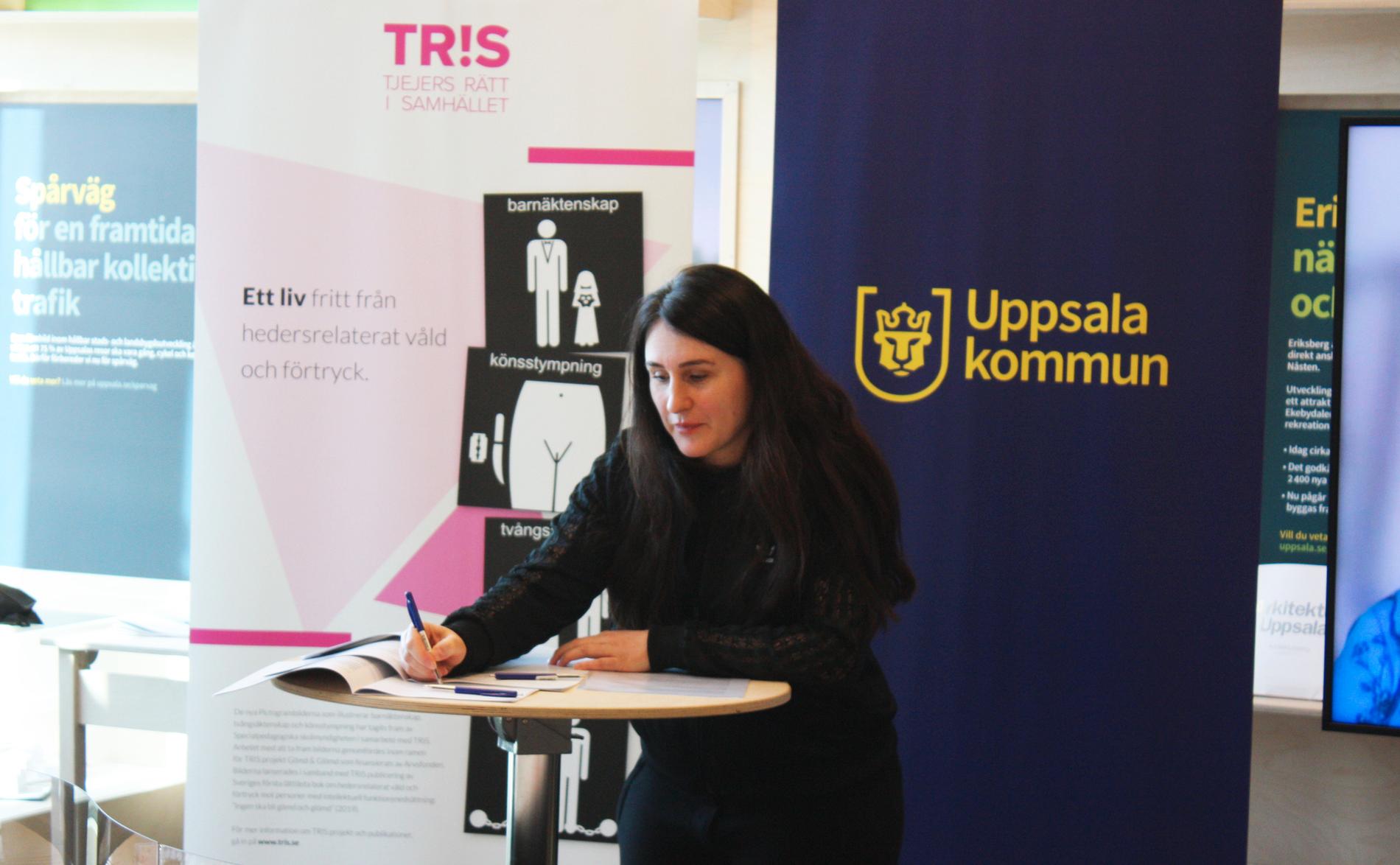 Talin Davidian, ordförande TRIS, signerar avtalet med Uppsala kommun.