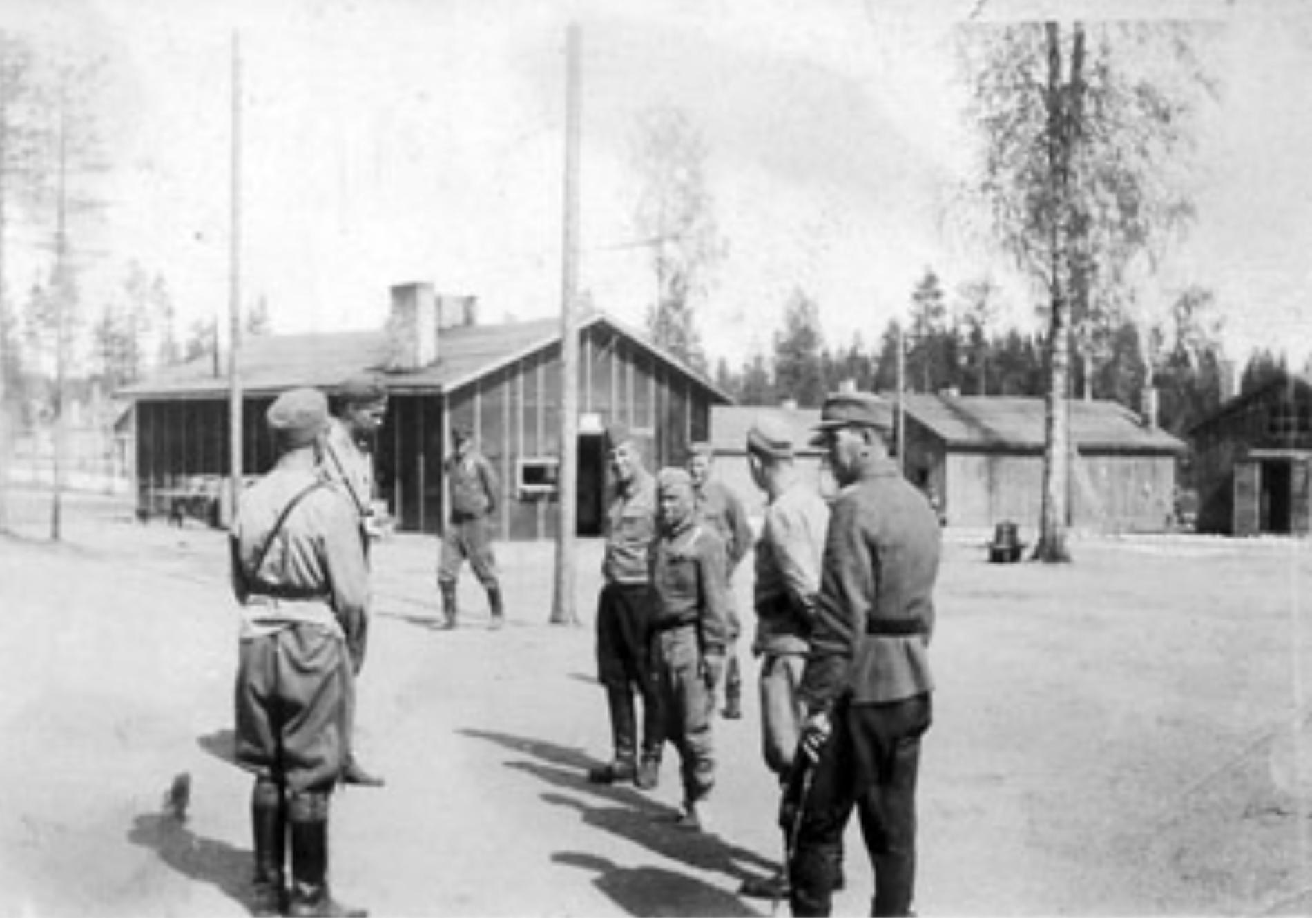 Finskt krigsfångeläger på östfronten med barfota krigsfånge i mitten. Fångarna var barfota för att hindra dem från att fly och dessutom ansågs de ovärdiga att slita på skosulor. Dödligheten i de finska lägren var störst 1942 men fortsatte 1943–1944. Värst drabbades ryska etniciteter men även 20 pro- cent av de judiska fångarna avled.