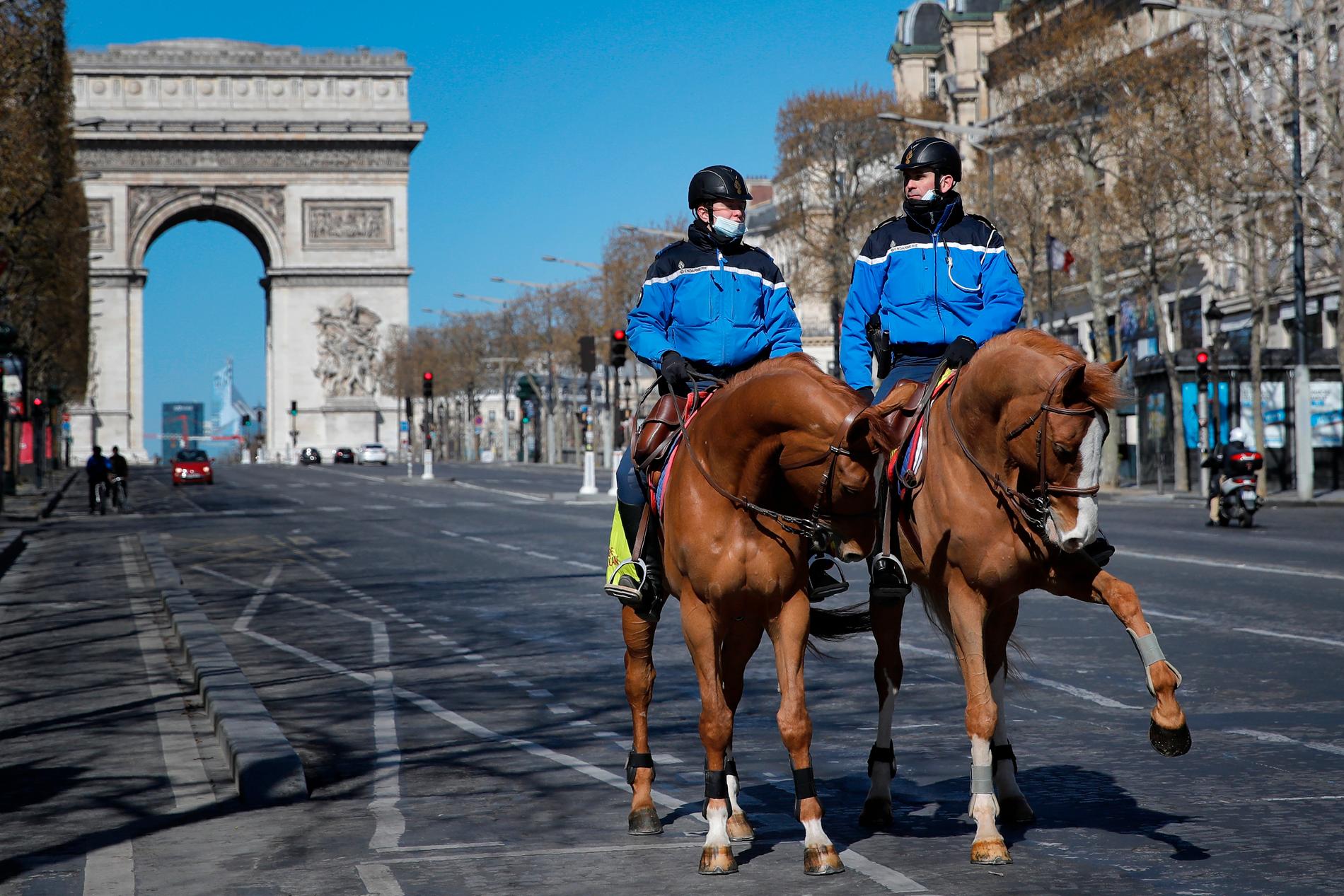 Poliser till häst på ett i övrigt ganska tomt Champs-Élysées i Paris.