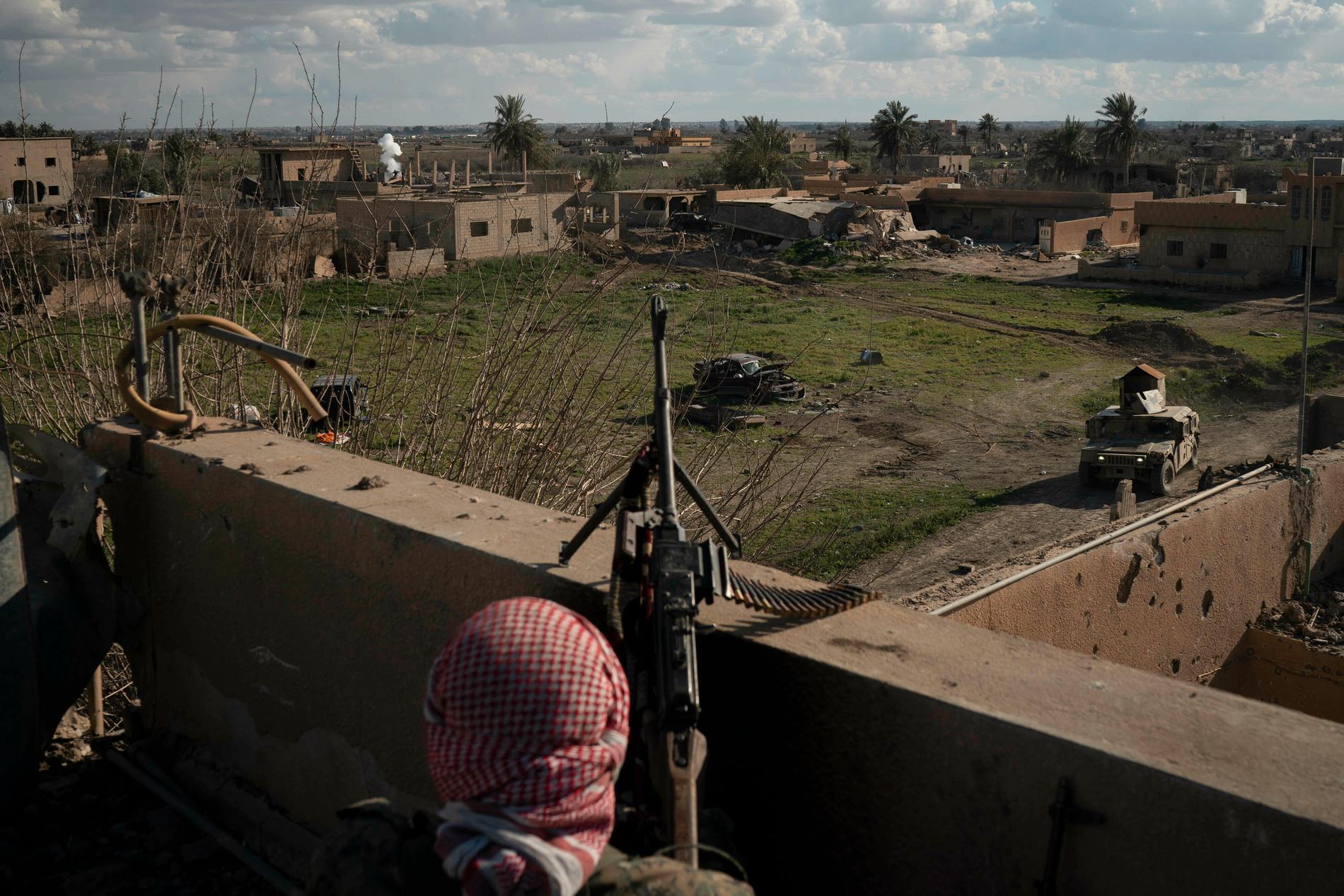 En soldat från alliansen SDF på ett tak nära den del av byn Baghouz i östra Syrien som fortfarande hålls av IS.