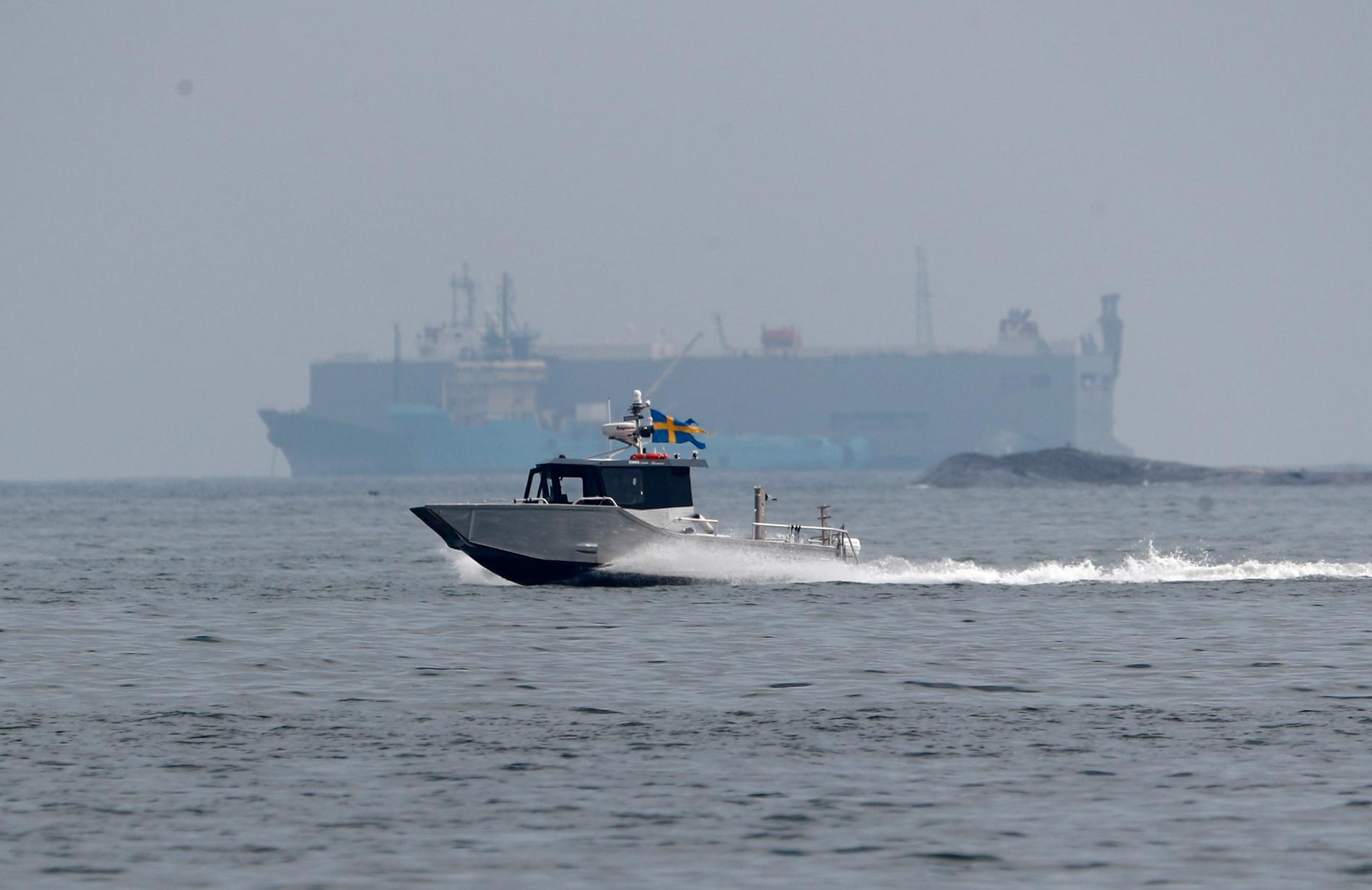 En båt passerar det grundstötta Makassar Highway som gick på grund i Tjusts skärgård norr om Västervik den 23 juli. Fartyget har läckt olja som nått flera mindre öar i närheten.