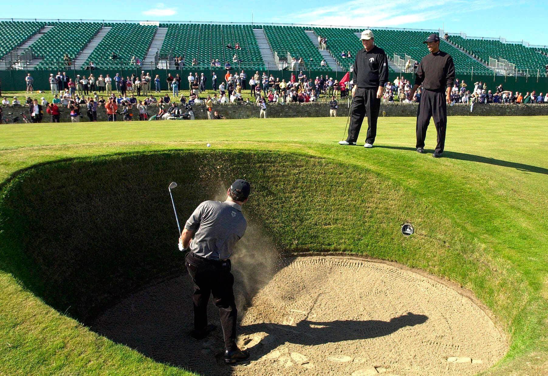 KNIVIGT Mark O'Meara slår ett slag ur bunkern bredvid green på det sjuttonde hålet på British Open 2000. Tiger Woods tittar på.