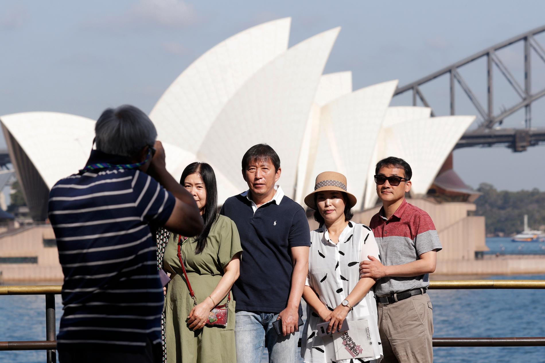 Turister låter fotografera sig framför Sydneys berömda operahus, i januari 2020, innan Australiens gränser stängdes. Internationella turister kommer troligen inte att kunna besöka landet förrän tidigast i mitten av 2022.