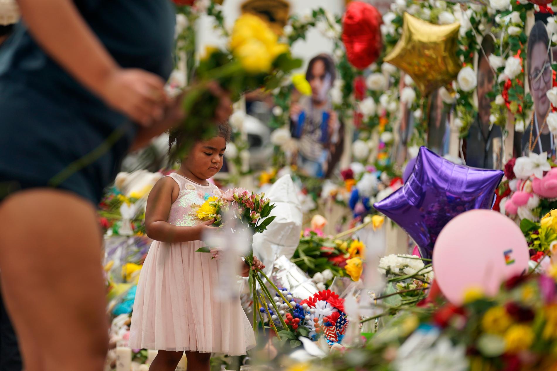 En flicka lägger ned en blomma till minne för de dödade. 