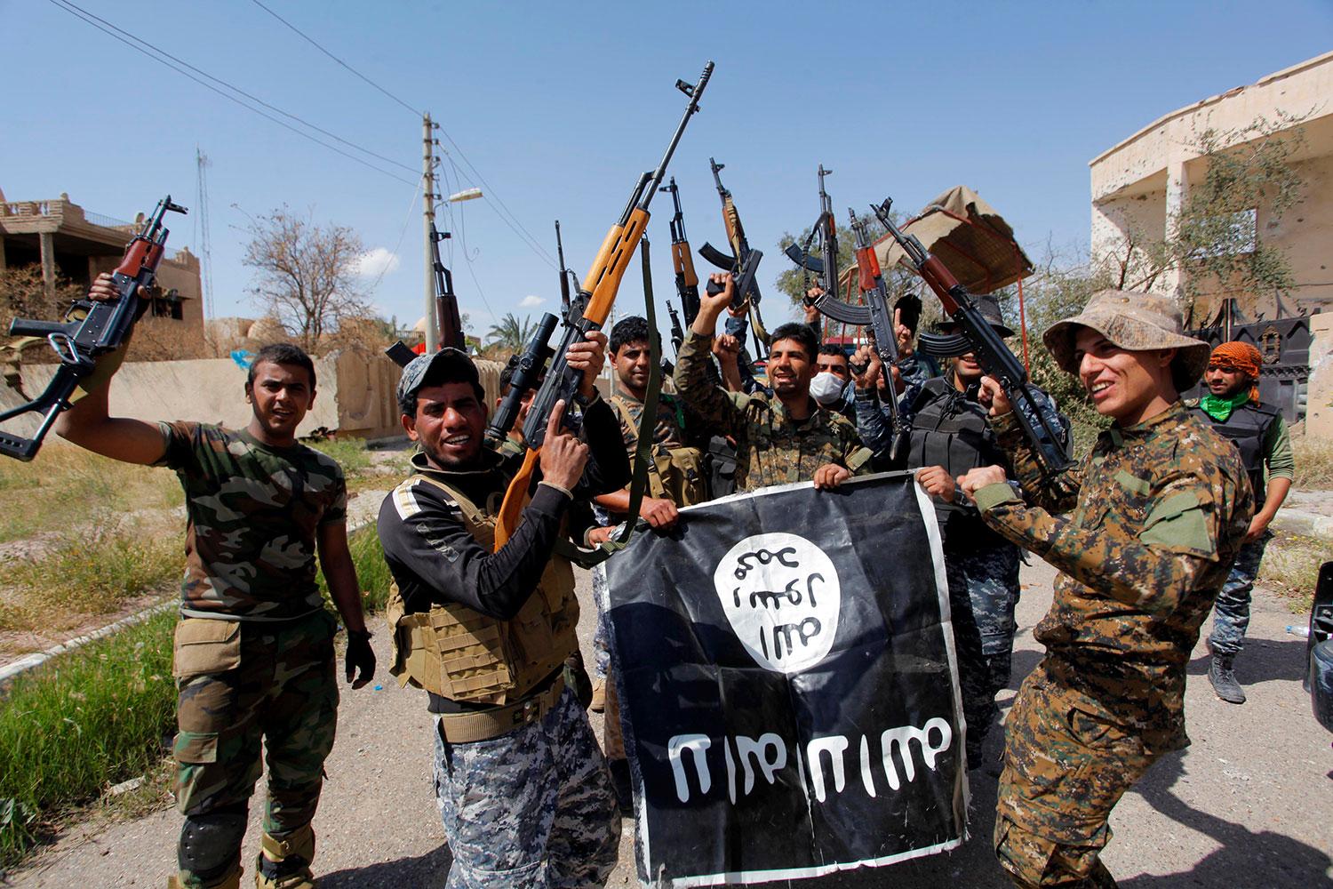 Irakiska säkerhetsstyrkor och shiamiliser med en IS-flagga i Tikrit.