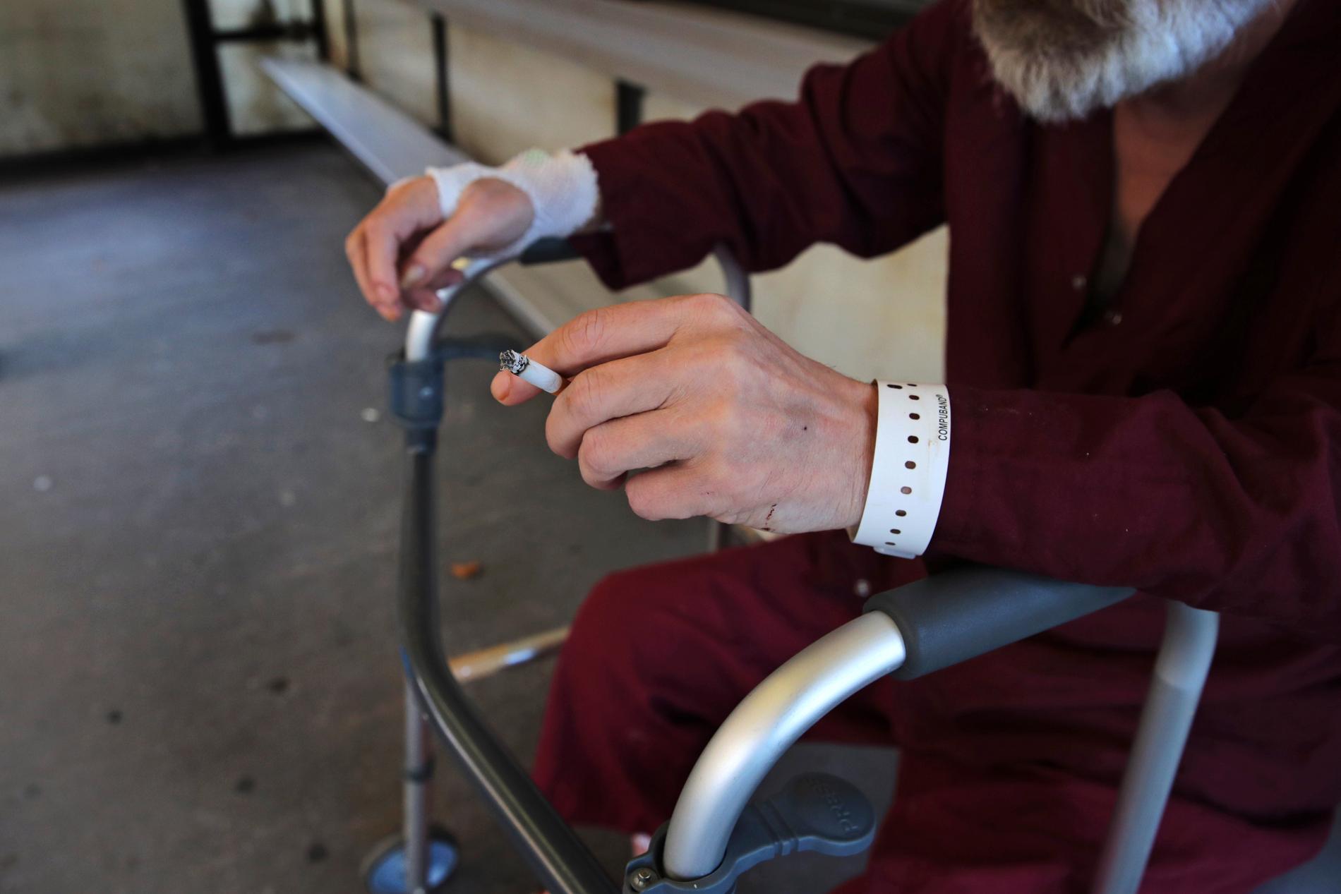 En äldre man vilar sig på rullatorn medan han tar en cigarett på ett sjukhus i Boston i USA. Sjukhuset har nyligen beslutat att förbjuda rökning på sjukhusområdet. De senaste 20 åren har många länder i världen infört starkare kontroll av tobak, delvis på grund av WHO:s ramkonvention för tobakskontroll.