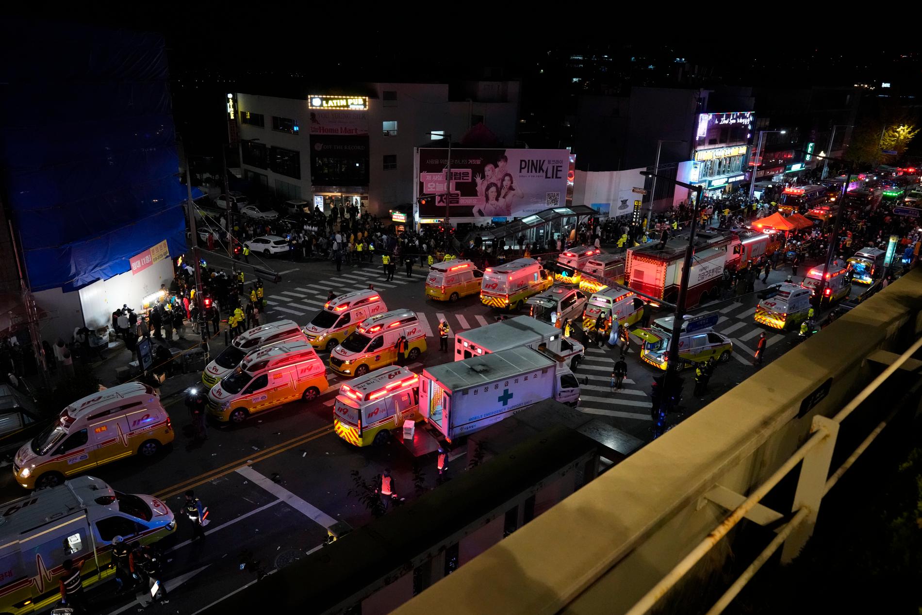 Räddningspersonal på plats på Itaewon street, utanför hotellet. Uppe till vänster i bilden syns tunnelbaneuppgången där folk fortsätter komma till området.