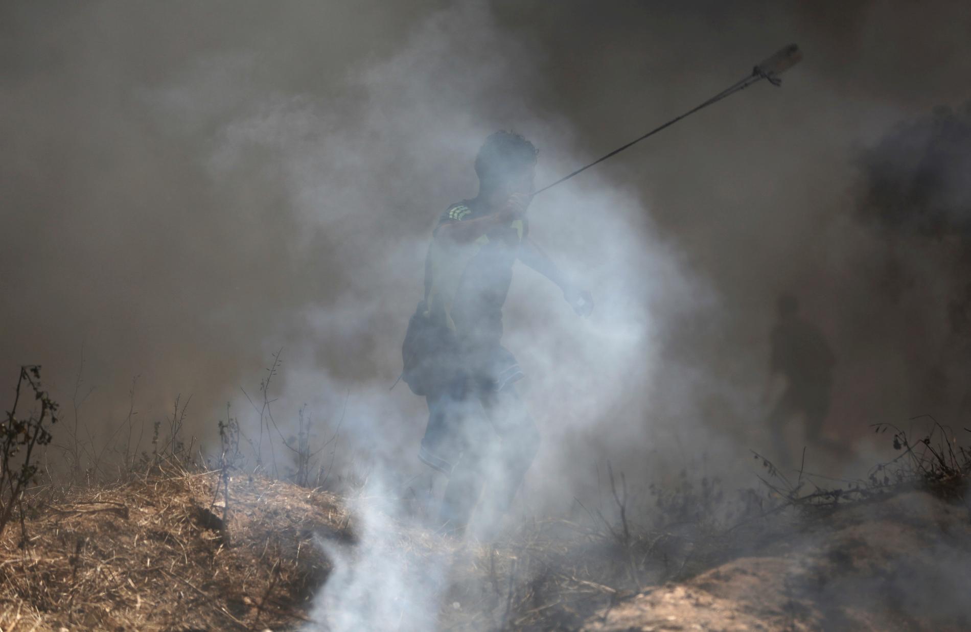 En palestinsk man slungar sten mot israeliska soldater under fredagens demonstrationer i Gaza.