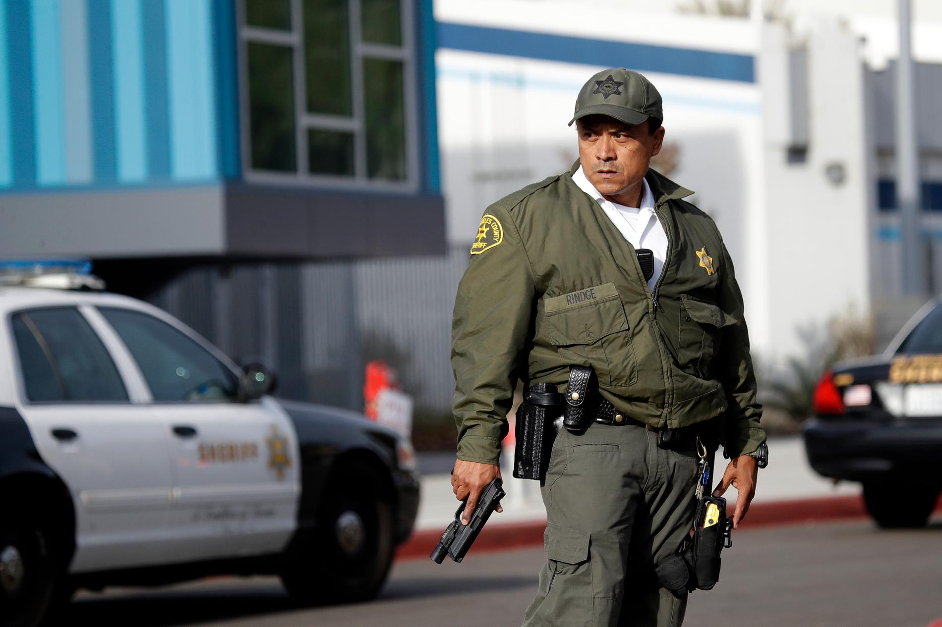 En polis från Los Angeles polisstation står med draget vapen utanför Saugus High School.