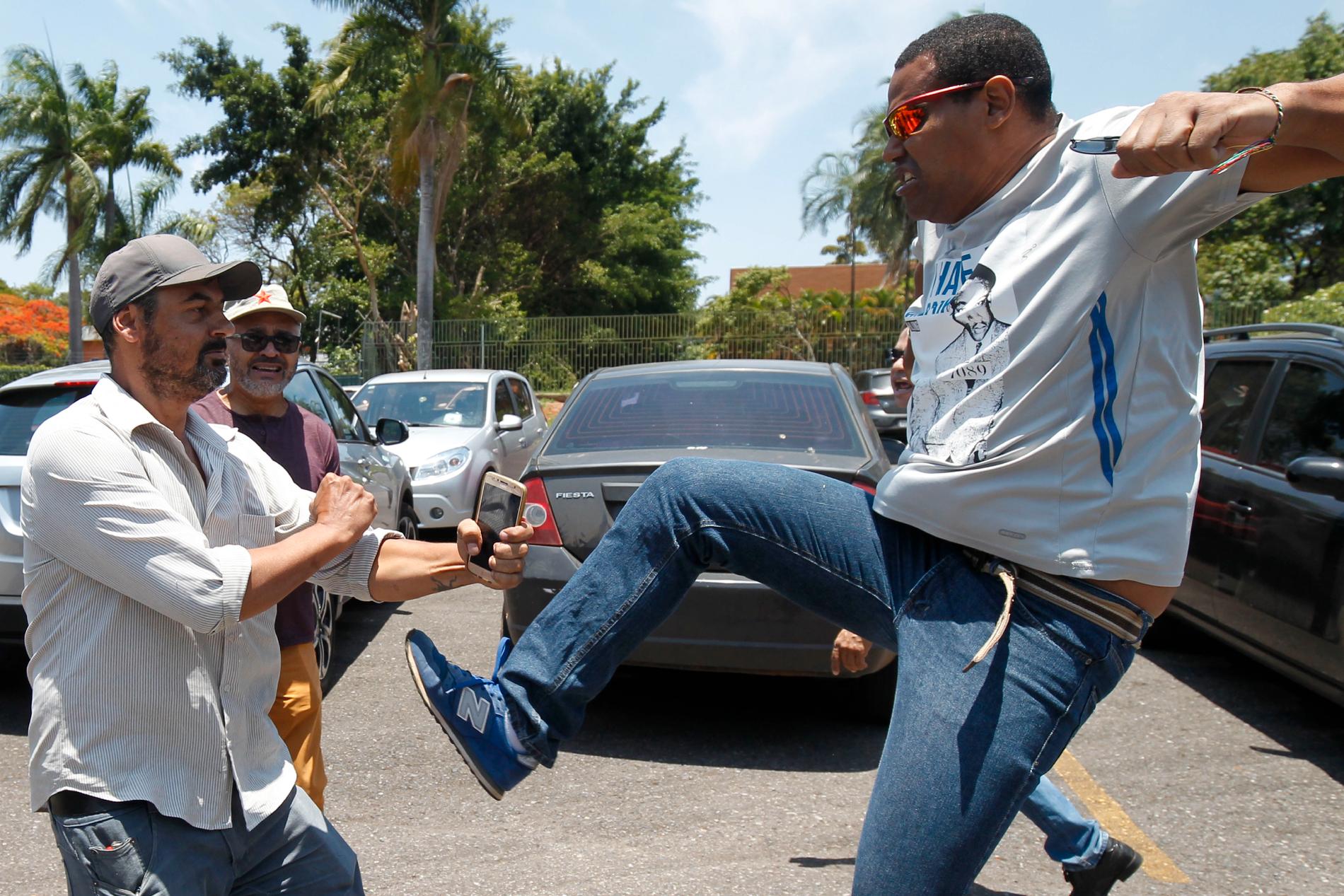 En Maduro-anhängare riktar en spark mot en meningsmotståndare utanför ambassaden.