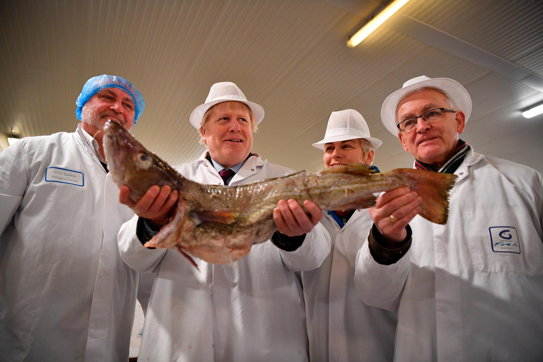 Boris Johnson håller upp en fisk.