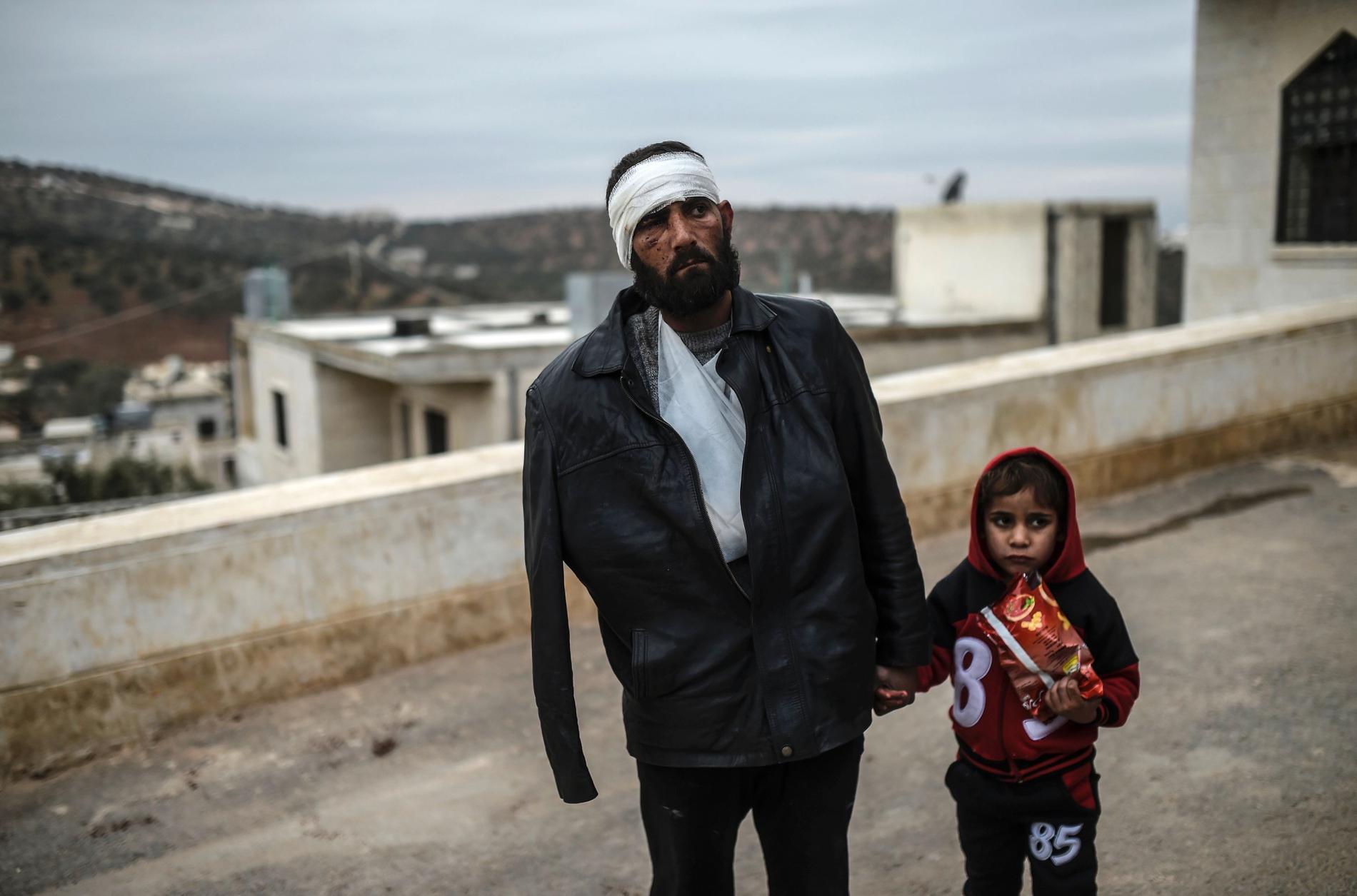En skadad syrisk man har precis anlänt till den syriska sidan av gränsen mot Turkiet, den 16 december. Han väntar med sin dotter utanför ett sjukhus.