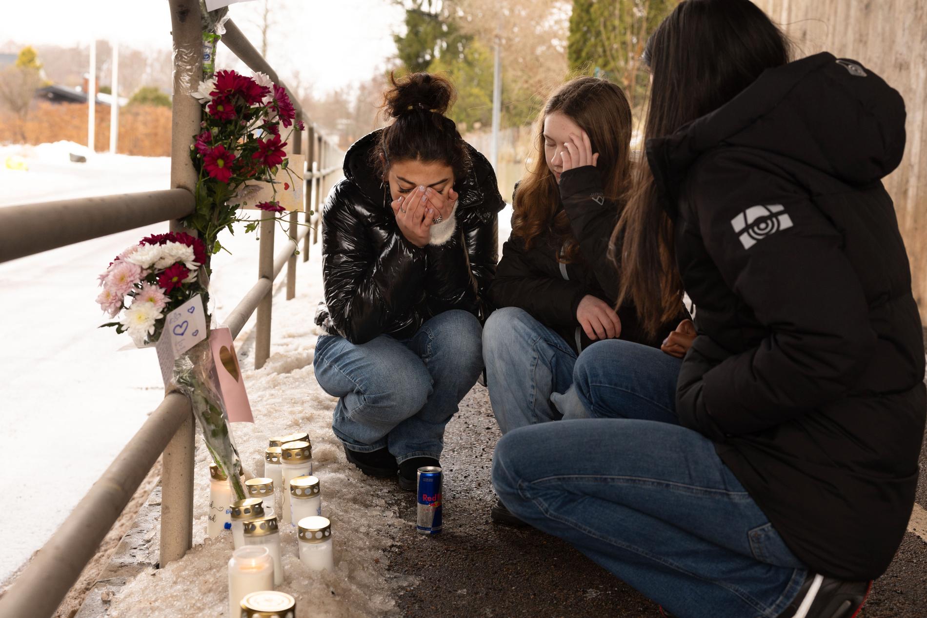 Vänner till 16-åringen i tårar framför tända ljus och blommor.