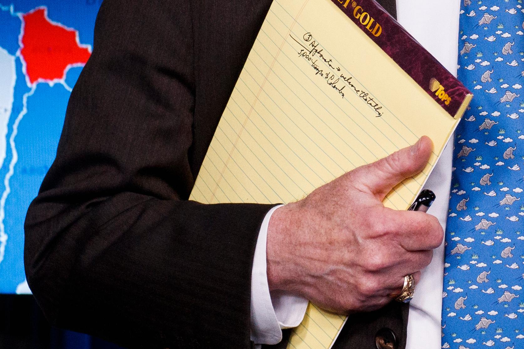 John Bolton med anteckningarna under armen vid måndagens pressträff i Vita huset.