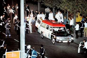 dramat är över Sent på kvällen den 28 augusti 1973 - efter nästan sex dygn - släpper polisen in gas i bankvalvet. Janne Olsson och Clark Olofsson ger upp. Här förs Olsson ut mellan två polismän.