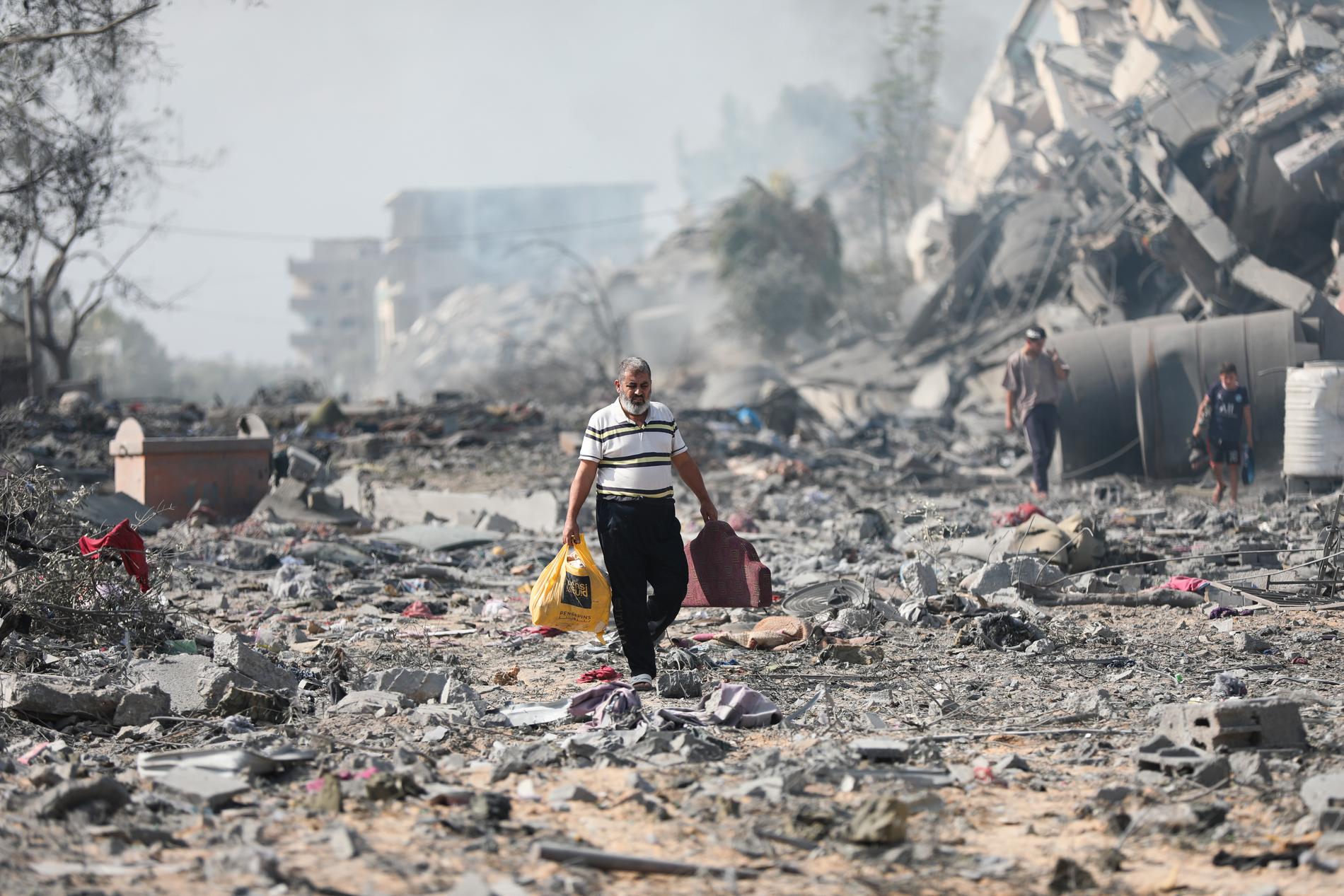 En palestinier går förbi sönderbombade byggnader i al-Zahra, Gaza, den 20 oktober, 2023.