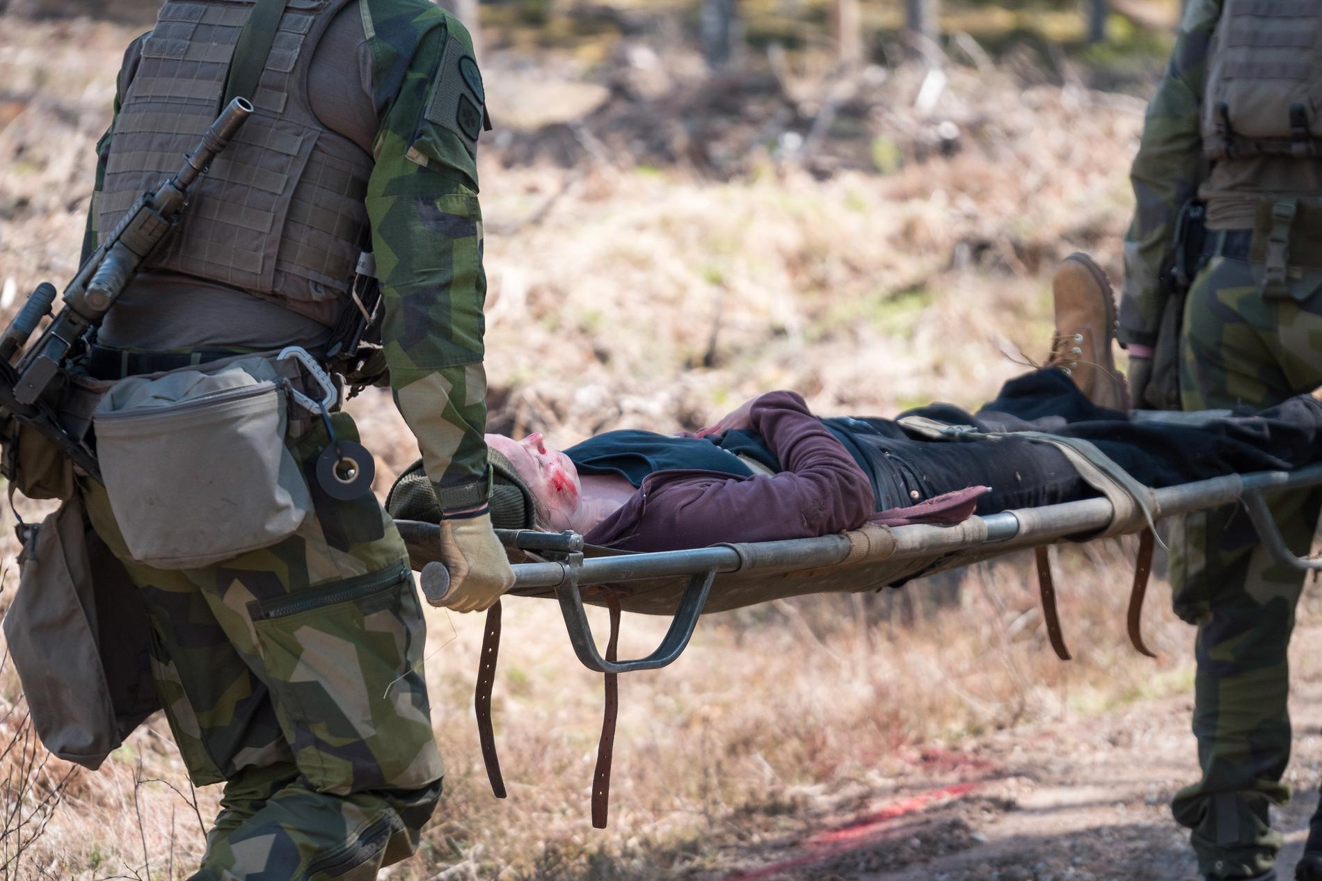 Soldater lyfter ”skademarkören” på bår från minfältet.