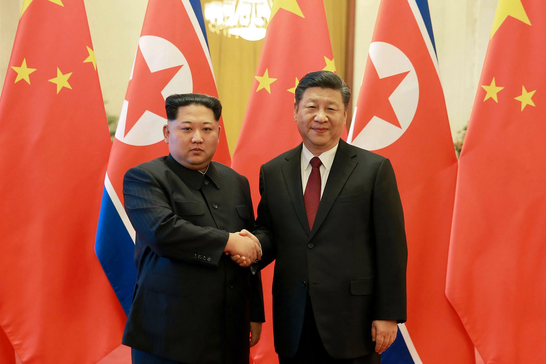 Kim Jong-un skakar hand med Kinas Xi Jinping .