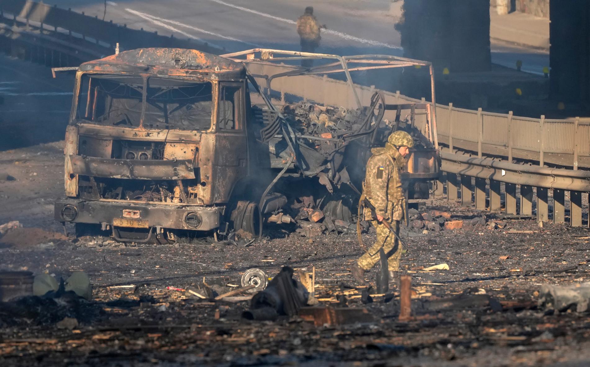 En ukrainsk soldat passerar ett utbränt fordon i Kiev på lördagen.