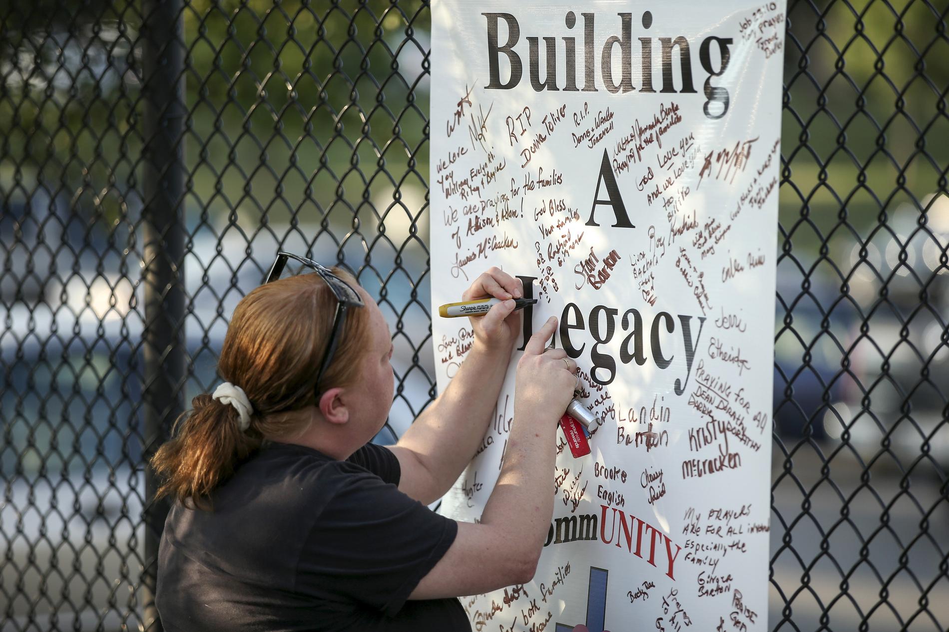 En kvinna skriver sitt namn på ett minnesmärke utanför WDBJ7-redaktionen i Roanoke, Virginia.