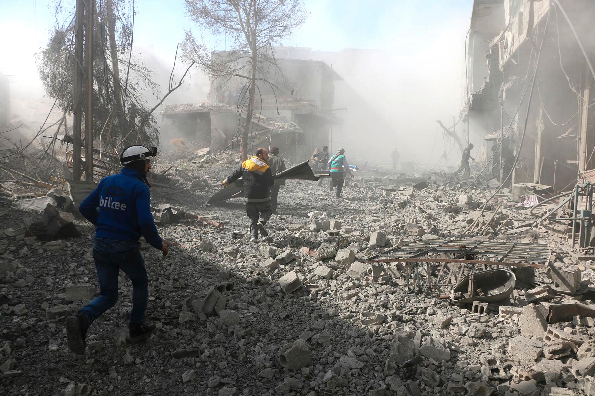 Medlemmar av den syriska civilförsvarsorganisationen Vita hjälmarna letar efter överlevande i spåren av ett flyganfall från den syriska regimen.