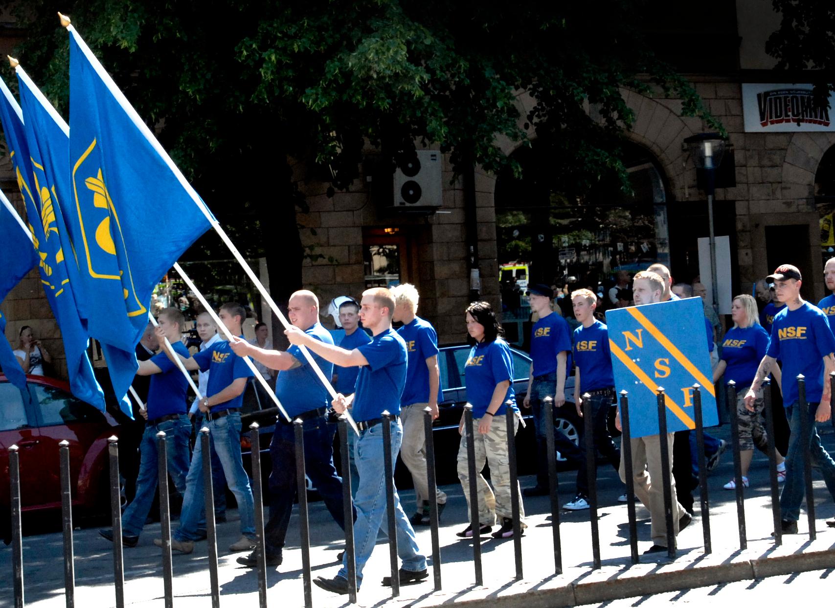 Nationalsocialistisk front med fanor under den högerextrema Folkets Marsch. Arkivbild. 