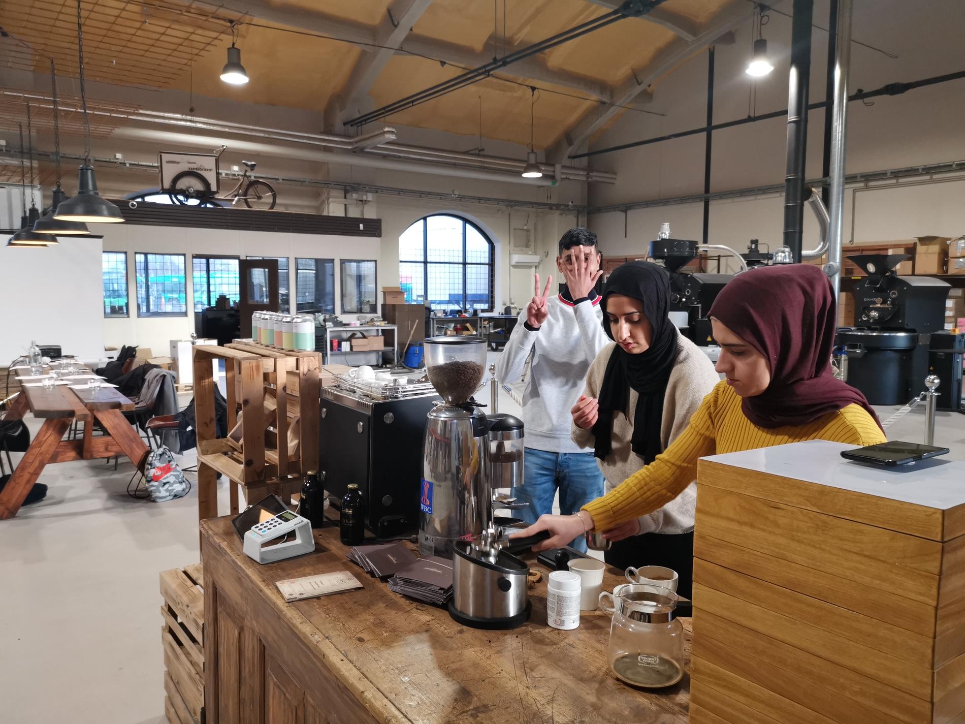Tre av eleverna på Malmö Barista Academy lär sig hur espressomaskinen fungerar.