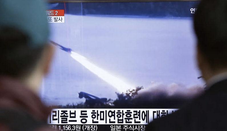 Två män i Seoul tittar på tv-bilder som visar den nordkoreanska robotskjutningen.