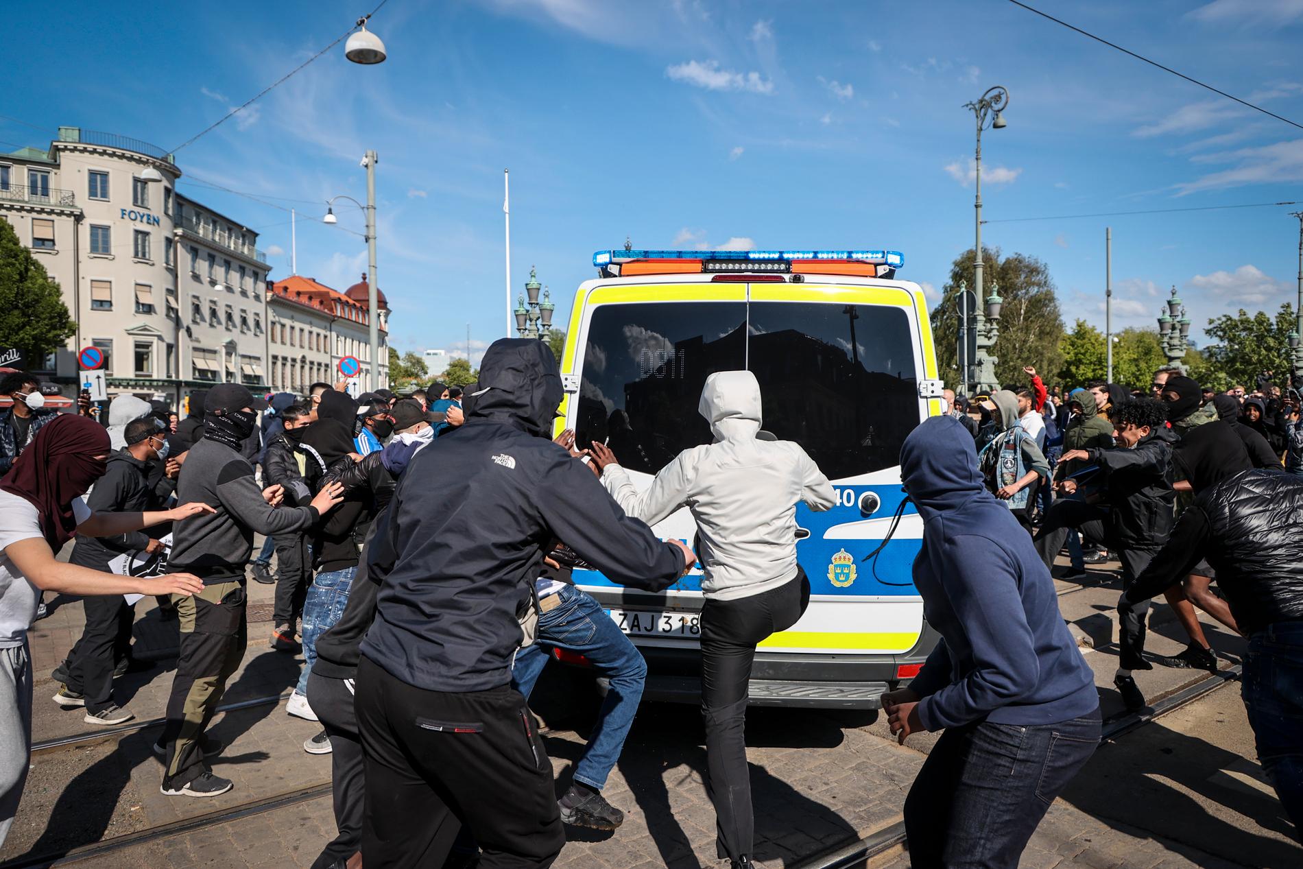 Ett antal personer sparkar på en polisbil på Avenyn, i centrala Göteborg. 