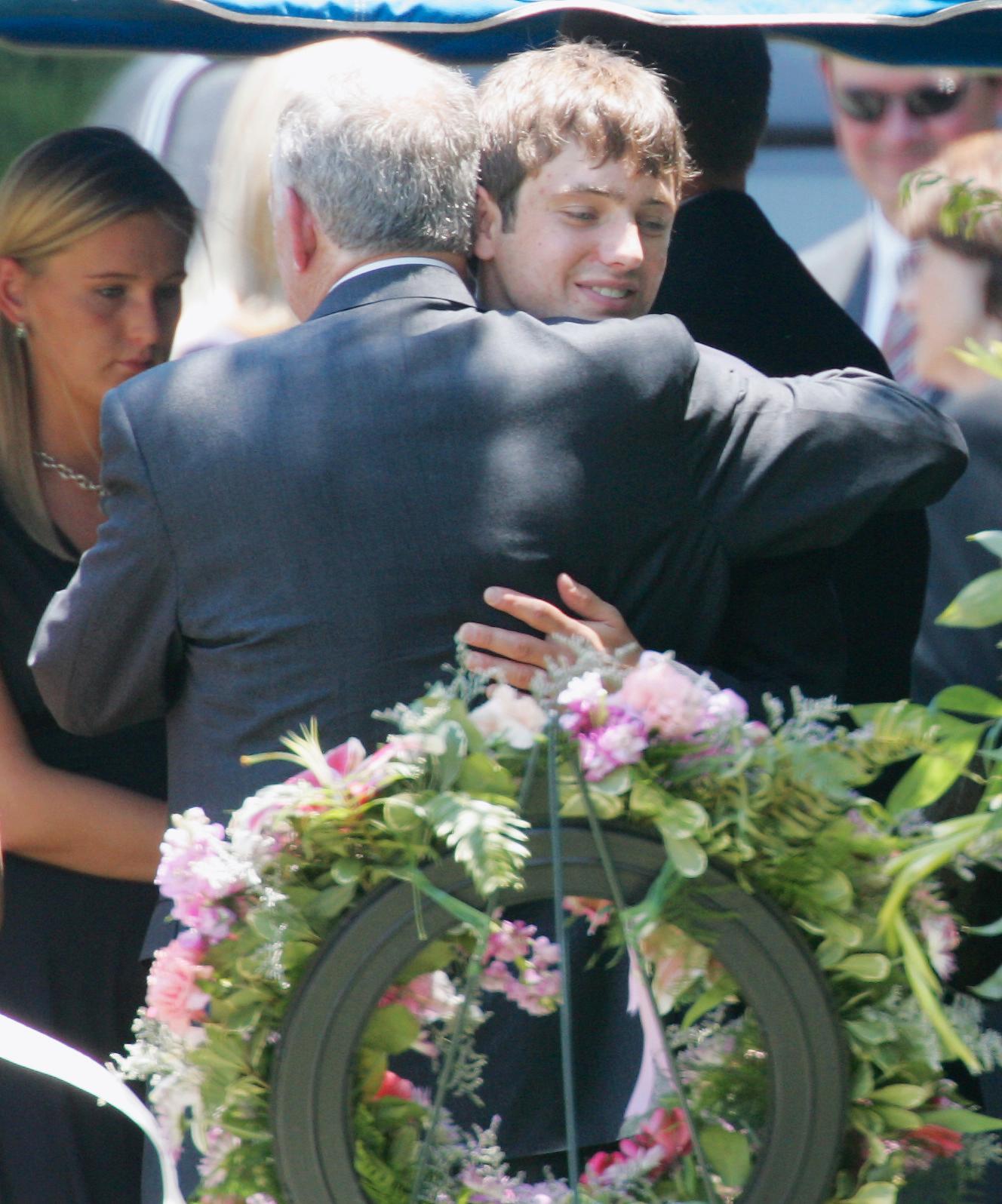 Burke Ramsey kramar om sin pappa John under en ceremoni 2006 vid gravplatsen för mamma Patsy och lillasyster JonBenét.