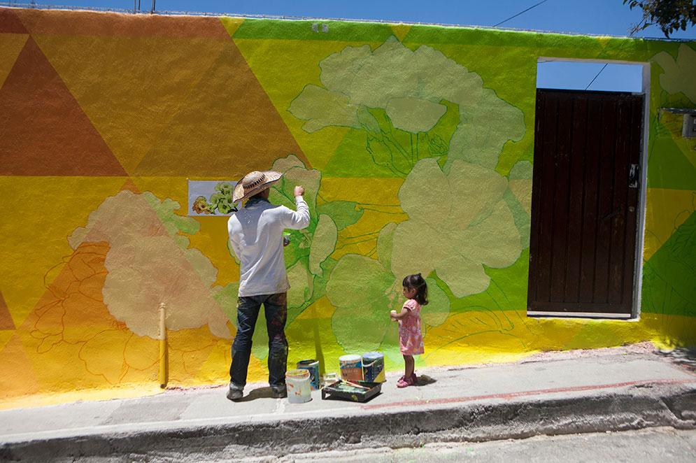 Carlos Duarte, till vänster, får sällskap av Regina Robles, right,när han målar en del av väggmålningen i Palmitas, Pachuca, Mexico,