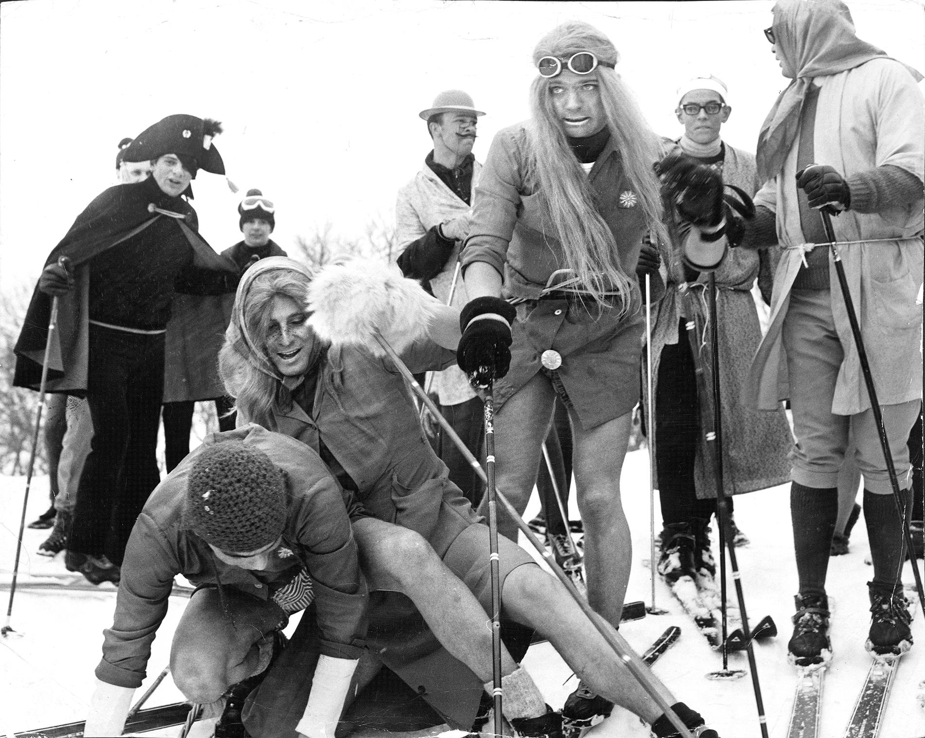 Maskerad på skidor Kronprins Carl Gustaf, 22, och hans vänner spexar i Storlien, 1968. Kronprinsen har peruk med långt blont hår, är barbent och har skidglasögon på huvudet.