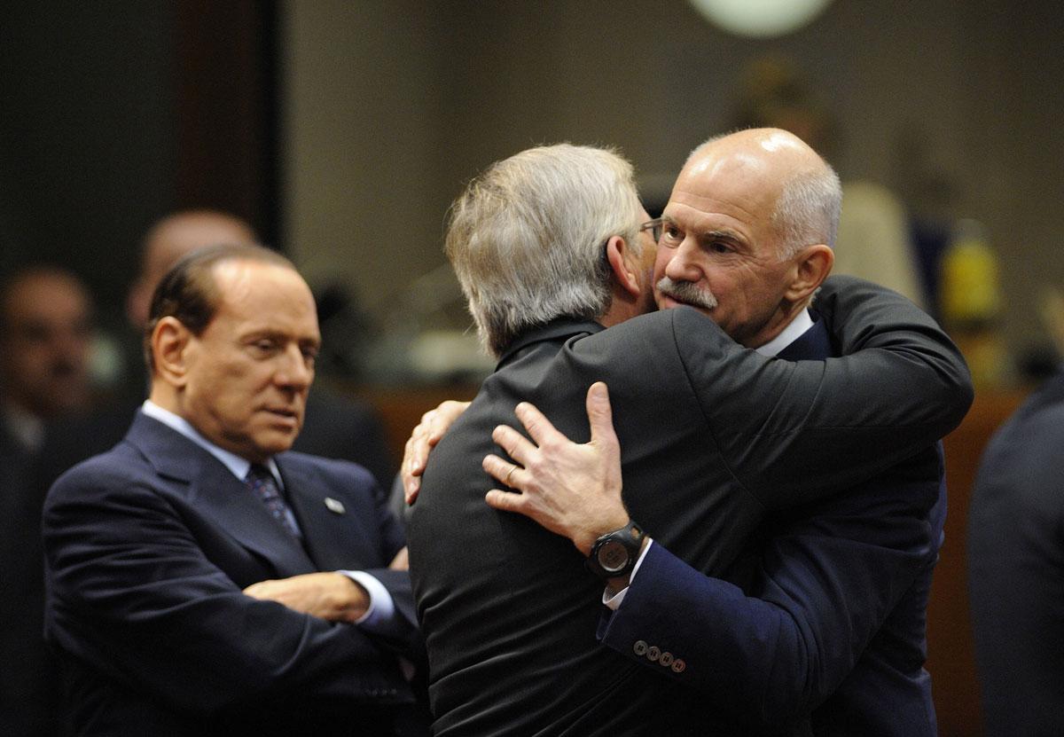 Greklands premiärminister George Papandreou kramas om av Luxemburgs premiärminister under EU-toppmötet. Till vänster Italiens premiärminister Silvio Berlusconi.