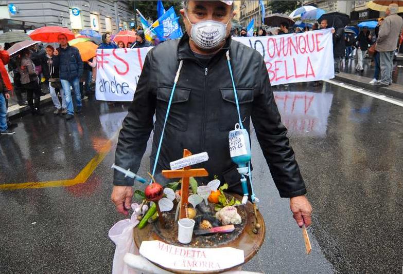 En man bär en miniatyr av en soptipp som han prytt med orden: "Jävla Camorra". Han är en av de närmare 100 000 som protesterade mot maffian i Neapel i går.