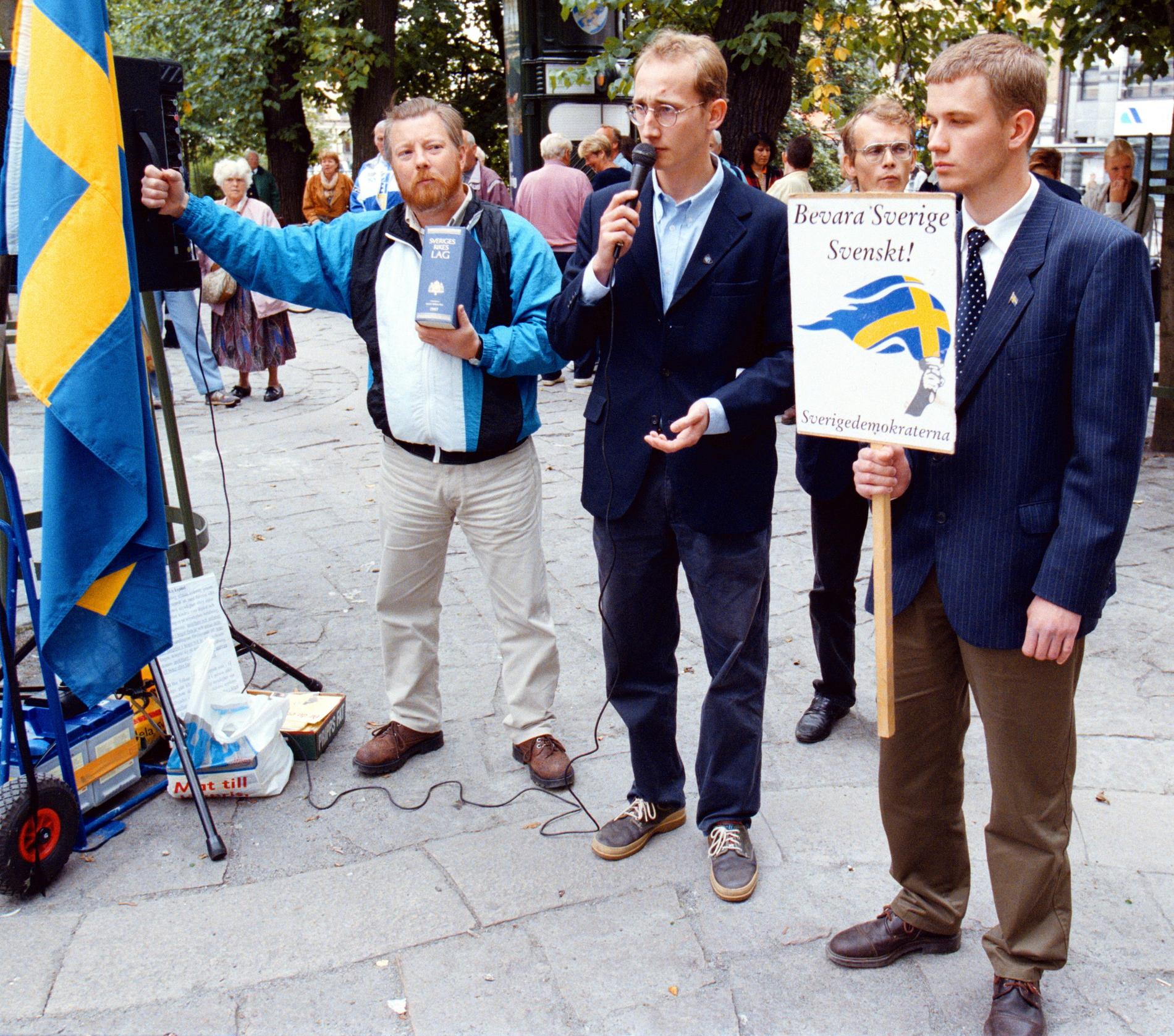 Sverigedemokraterna håller valmöte i Brunnsparken i Göteborg 1998. En av deltagarna håller upp en lagbok och en annan en skylt med texten ”Bevara Sverige svenskt”. 