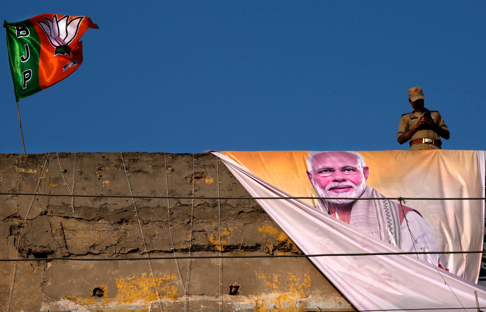 Premiärminister Narendra Modis porträtt syns numera överallt i Indien. Här står en polis på vakt ovanför ett valevenemang i Ghaziabad den 6 april.
