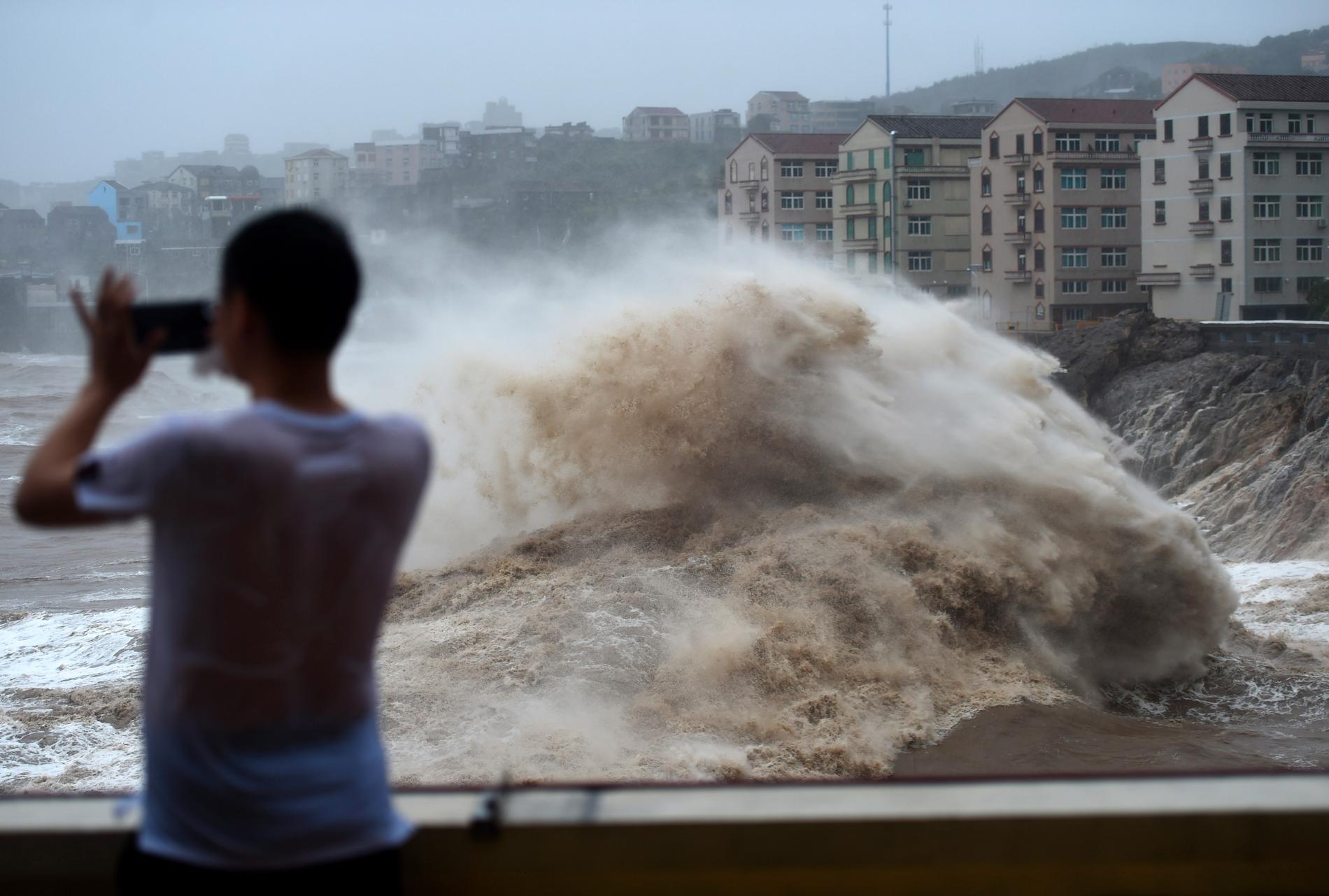 En man filmar när tyfonen Lekima drar in över den kinesiska staden Wenling med flera meter höga vågor.
