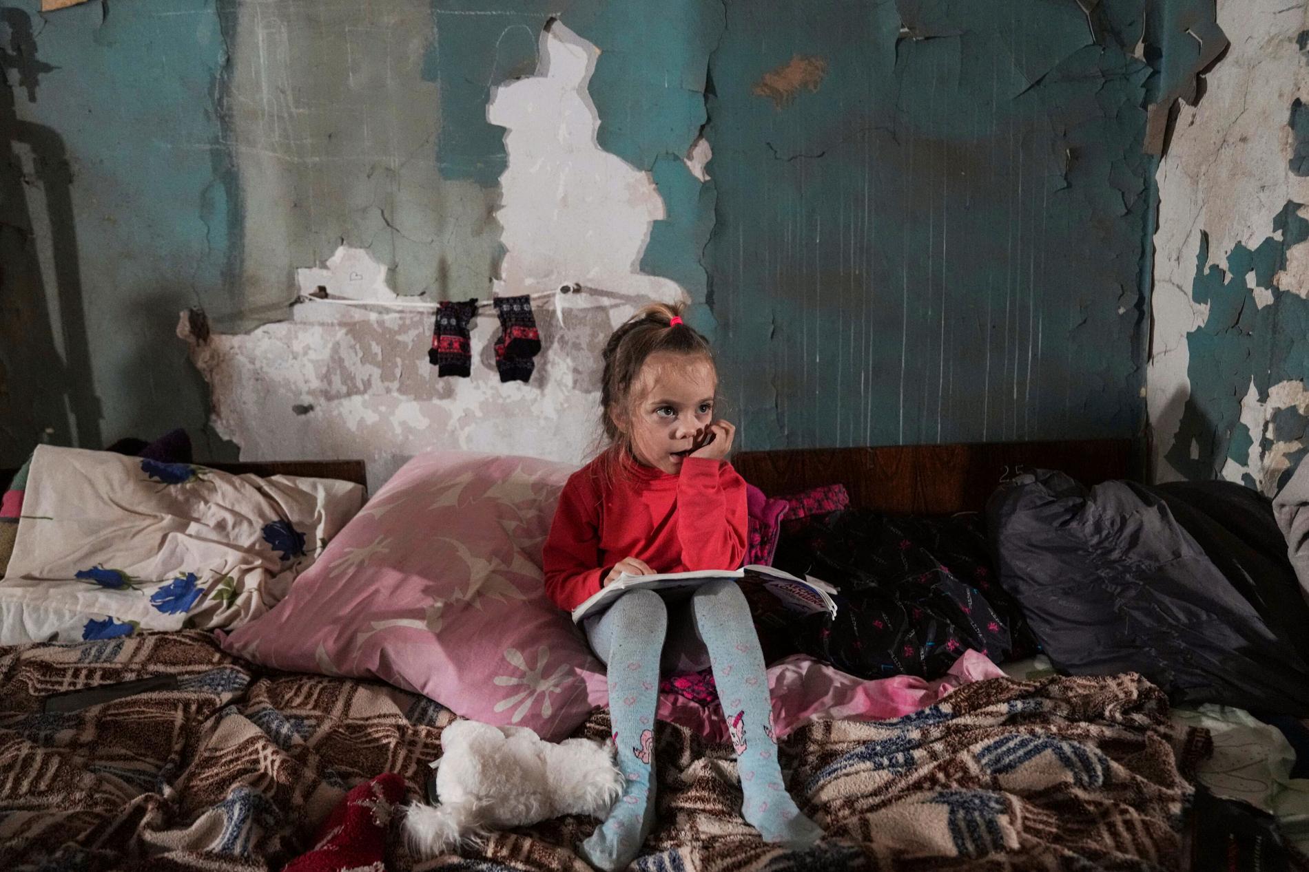 En flicka sitter i ett provisoriskt skyddsrum i Mariupol.