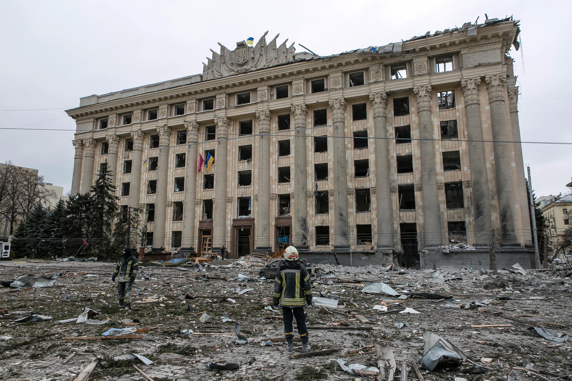 En ukrainsk räddningsarbetare tittar på stadshuset på centrala torget i Charkiv. Tisdag 1 mars utsattes byggnaden för ryska flygbombningar.  