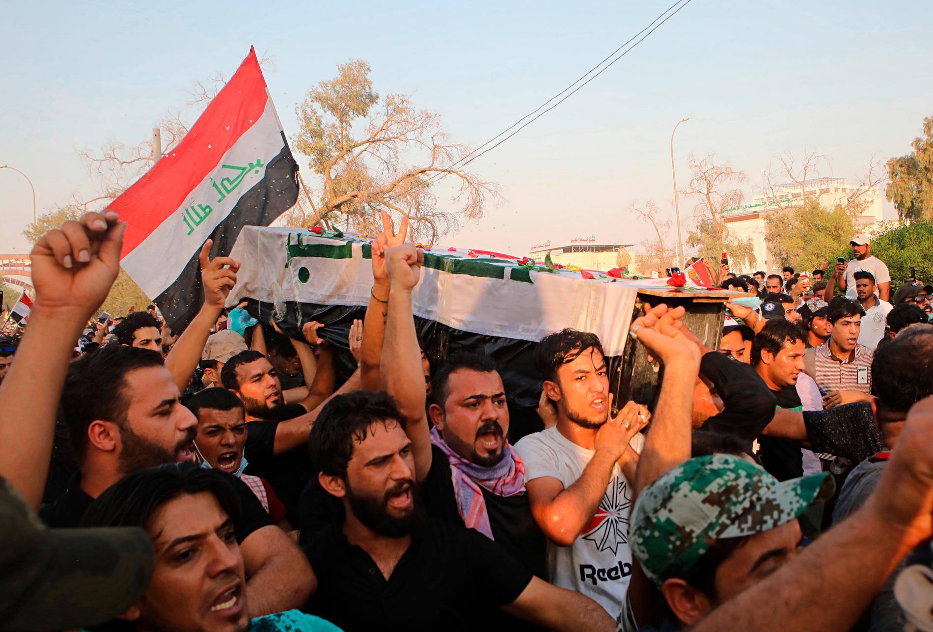 Demonstranter skanderar regeringskritiska slogans samtidigt som de bär kistan med kvarlevorna efter en aktivist som dödades i veckans sammandrabbningar i Basra i Irak.