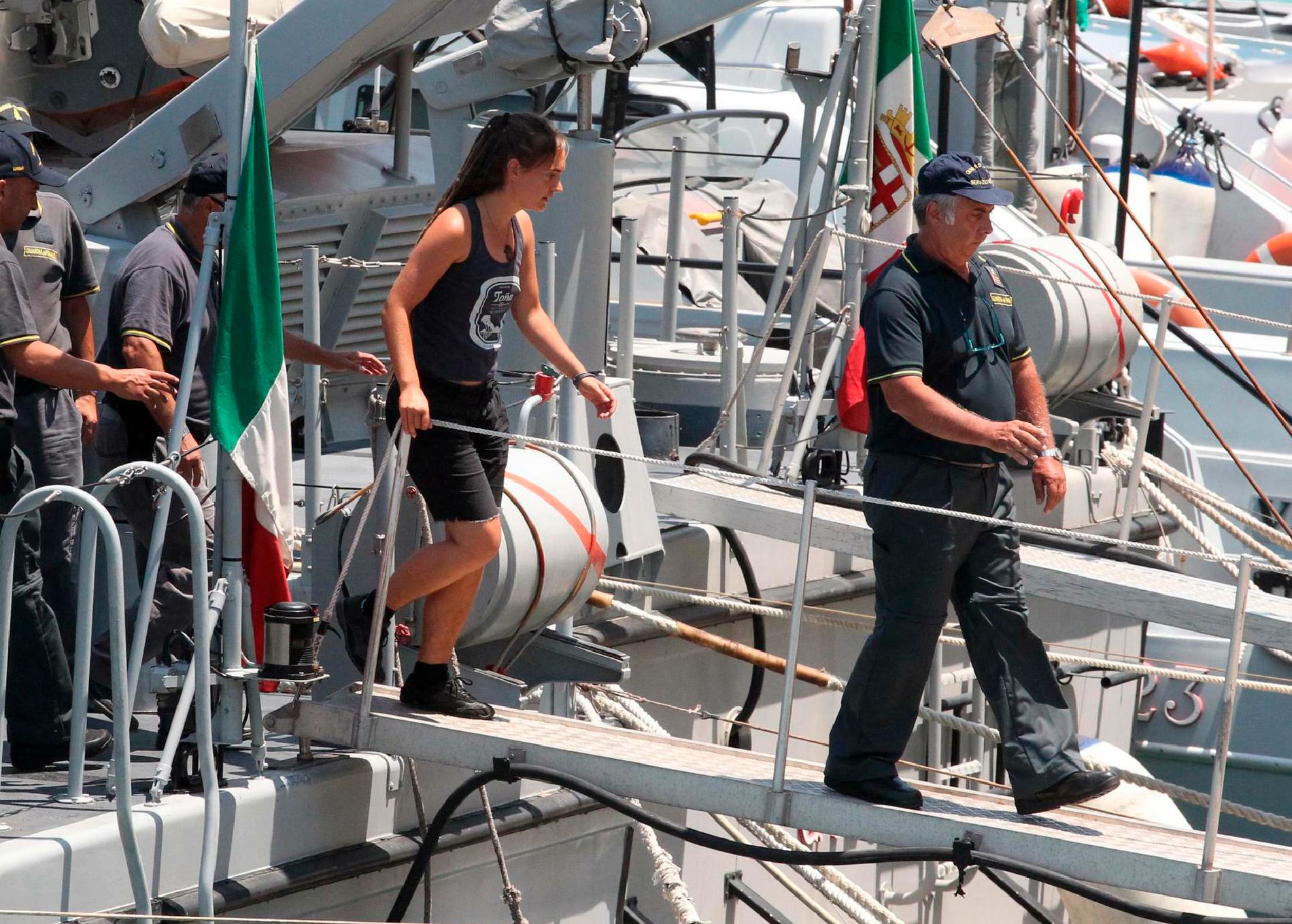 Carola Rackete går i land eskorterad av italiensk polis. Bild från 1 juli 2019.