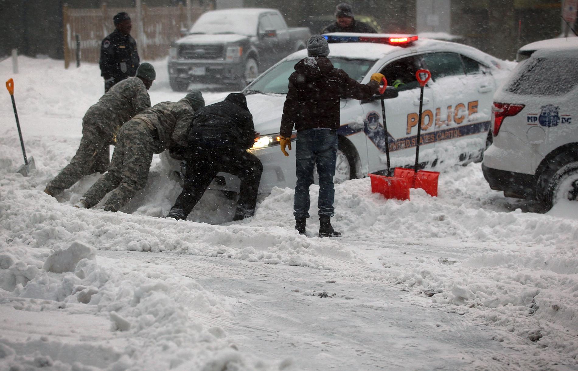 En polisbil har fastnat i snömassorna i Washington DC och får hjälp att komma loss.