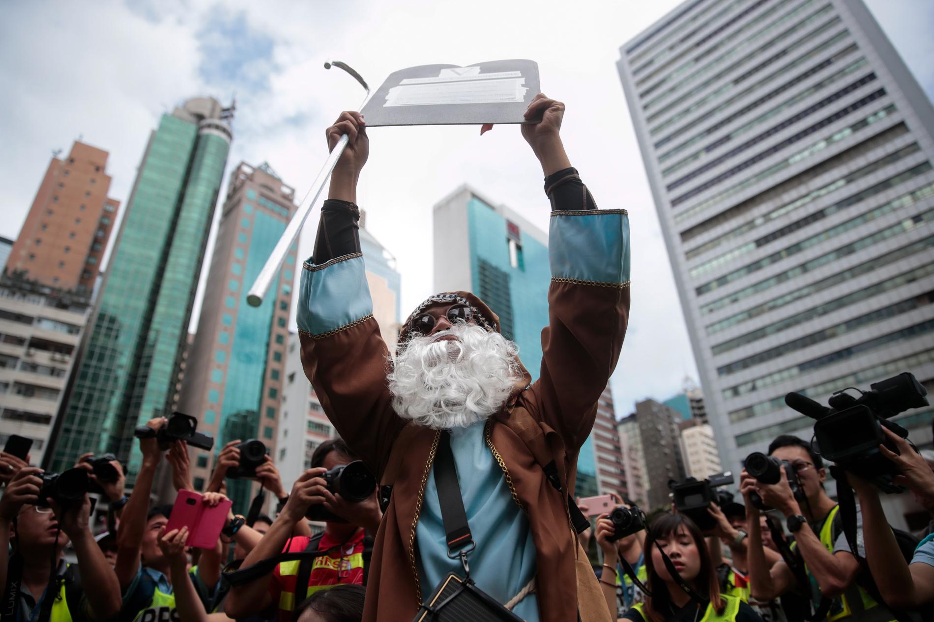 En demonstrant utklädd till Moses håller upp en stentavla vid en protest i Hongkong.